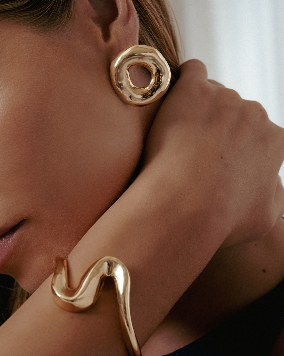 Melted circle earrings available in gold plated and rhodium plated finishes with sculptural curved design