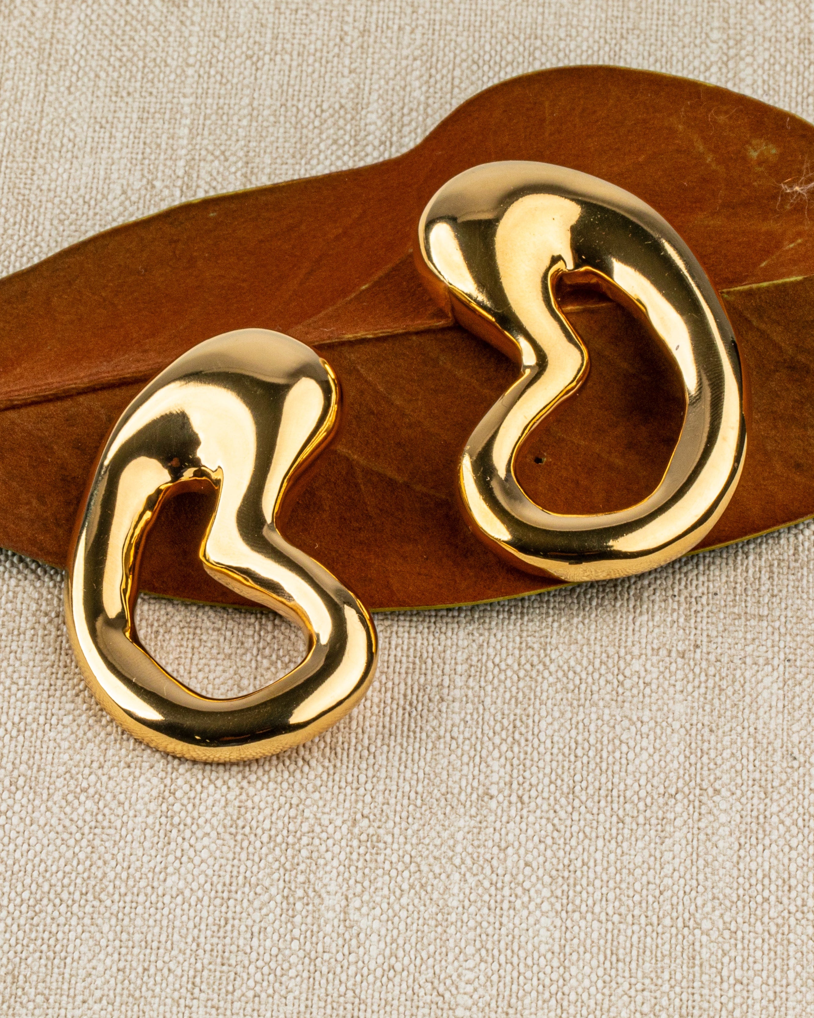 Gold plated organic sculptural earrings with fluid asymmetric curved design and polished finish, 61mm by 30mm