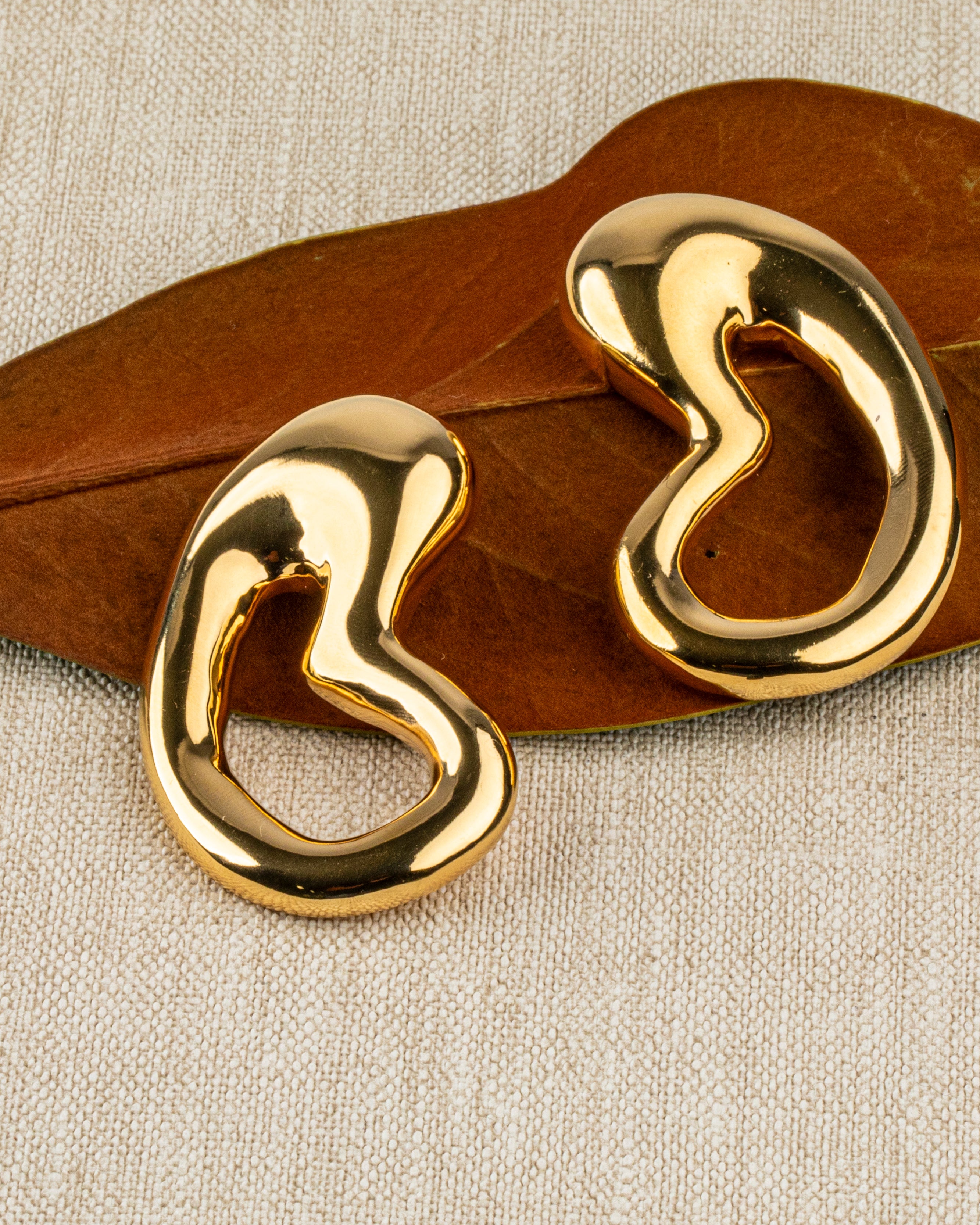 Gold plated organic sculptural earrings with fluid asymmetric curved design and polished finish, 61mm by 30mm