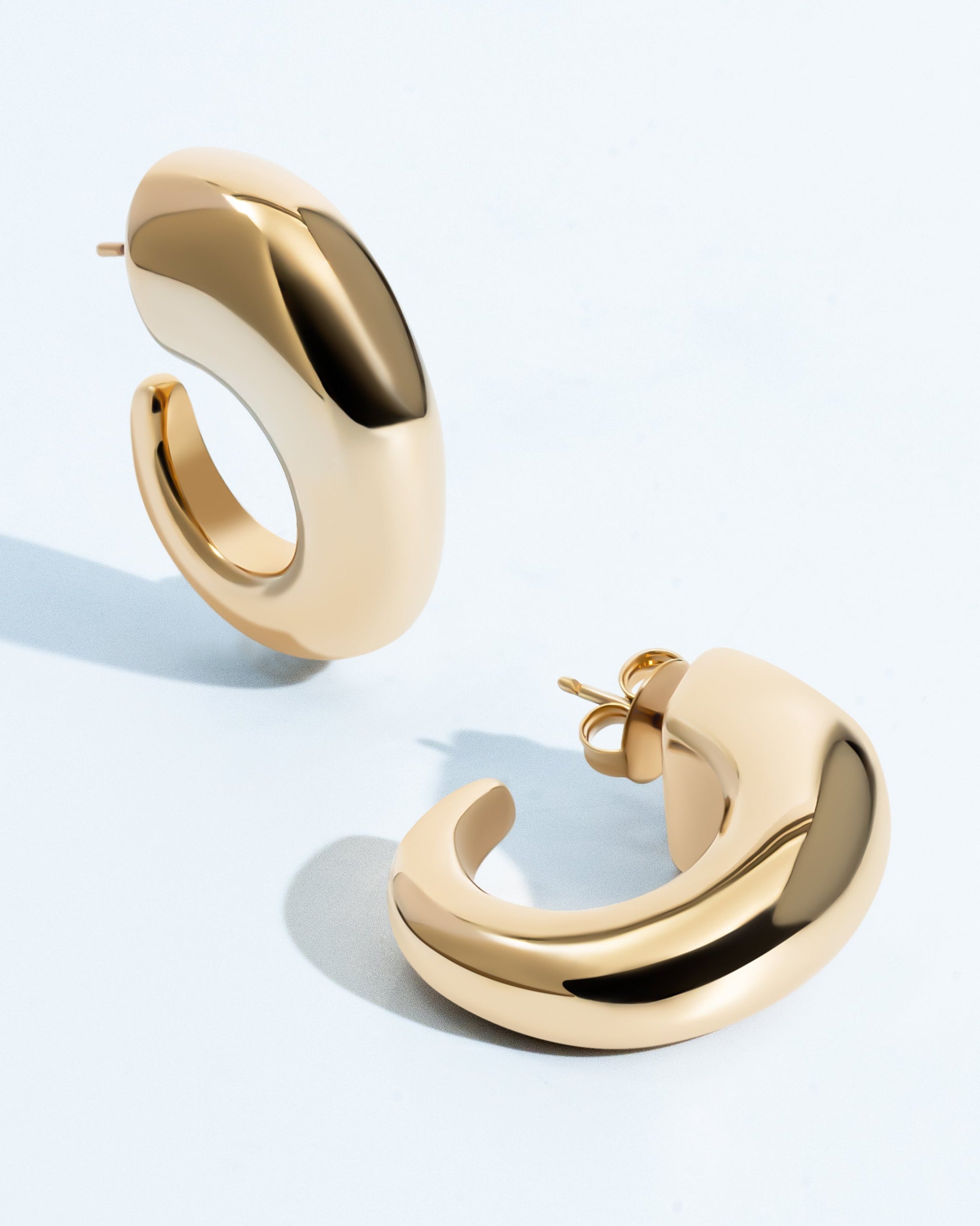 Oval open hoop earrings available in gold plated and rhodium plated finishes with sculptural thick design