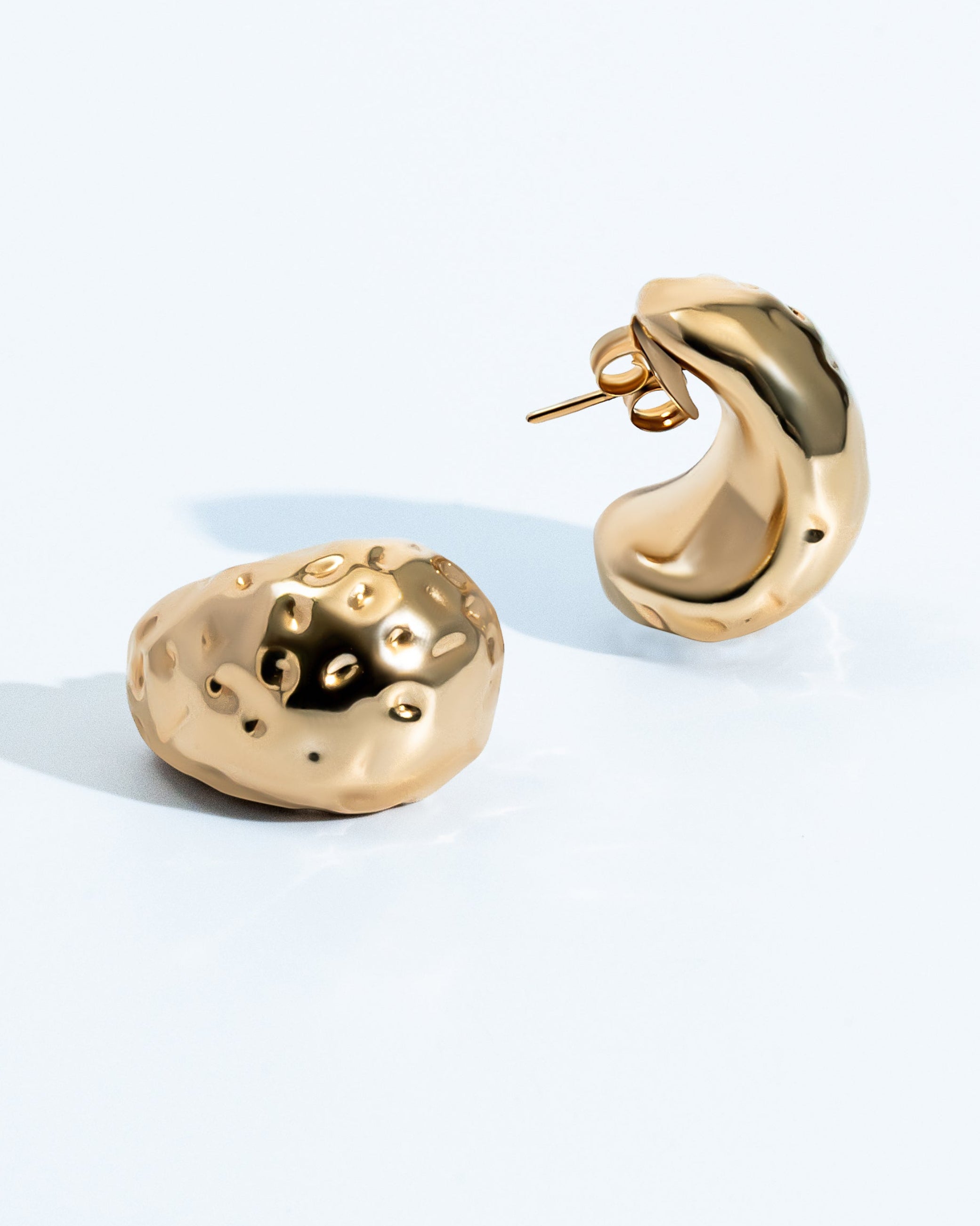 Gold sculptural earrings with compact organic texture and polished finish