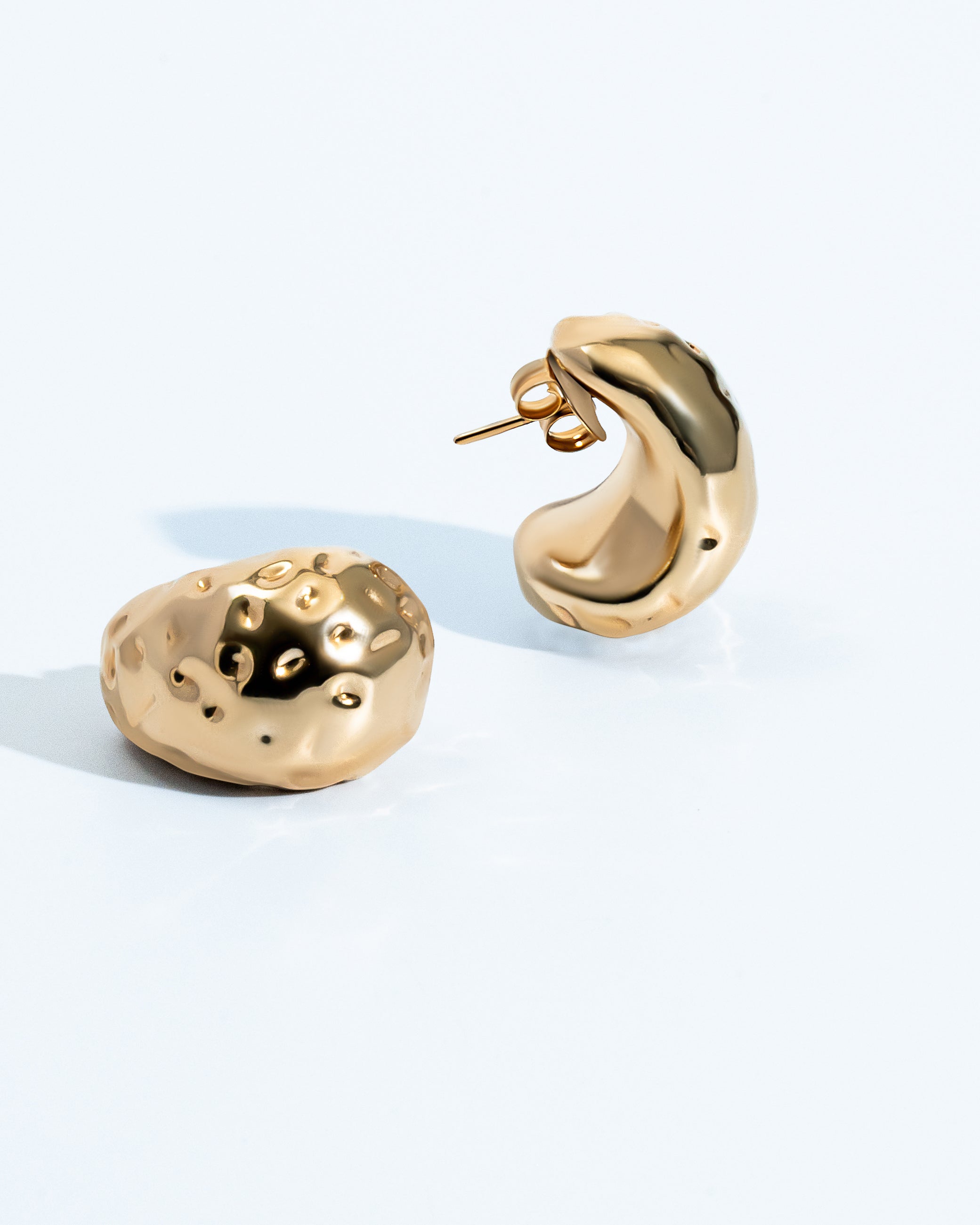 Gold sculptural earrings with compact organic texture and polished finish