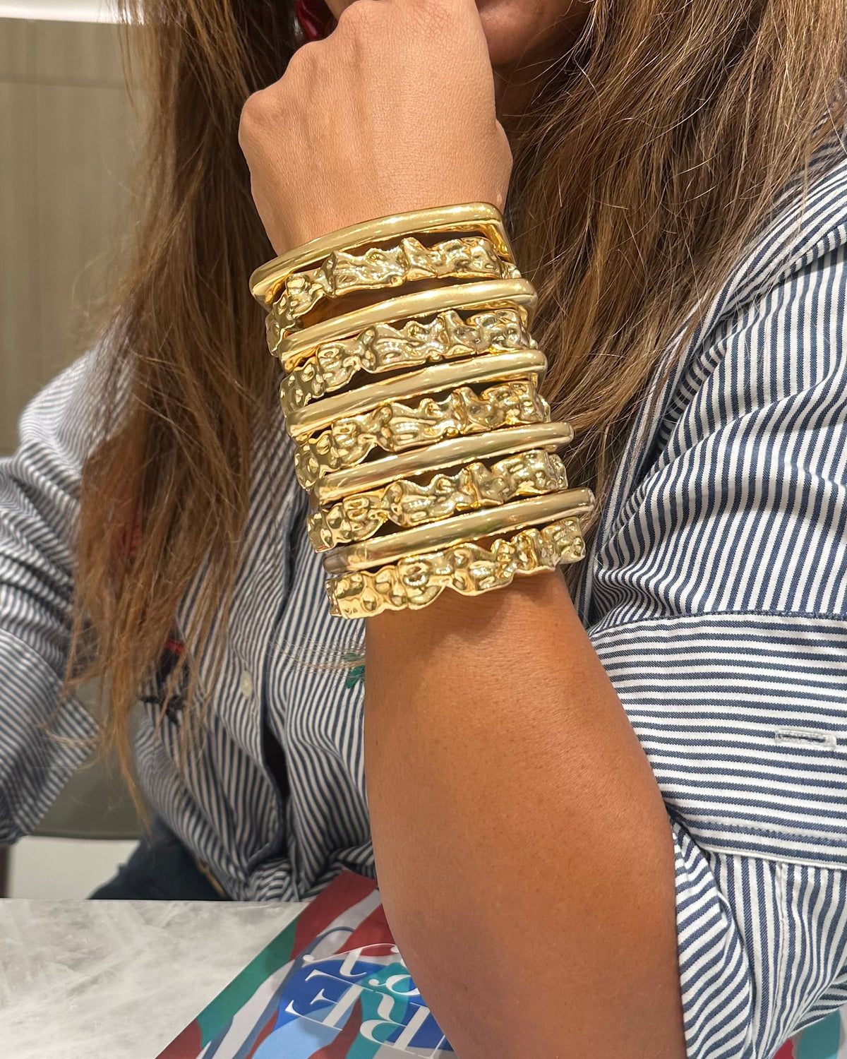 Sculptural gold cuff bracelet with irregular hammered texture on the arm