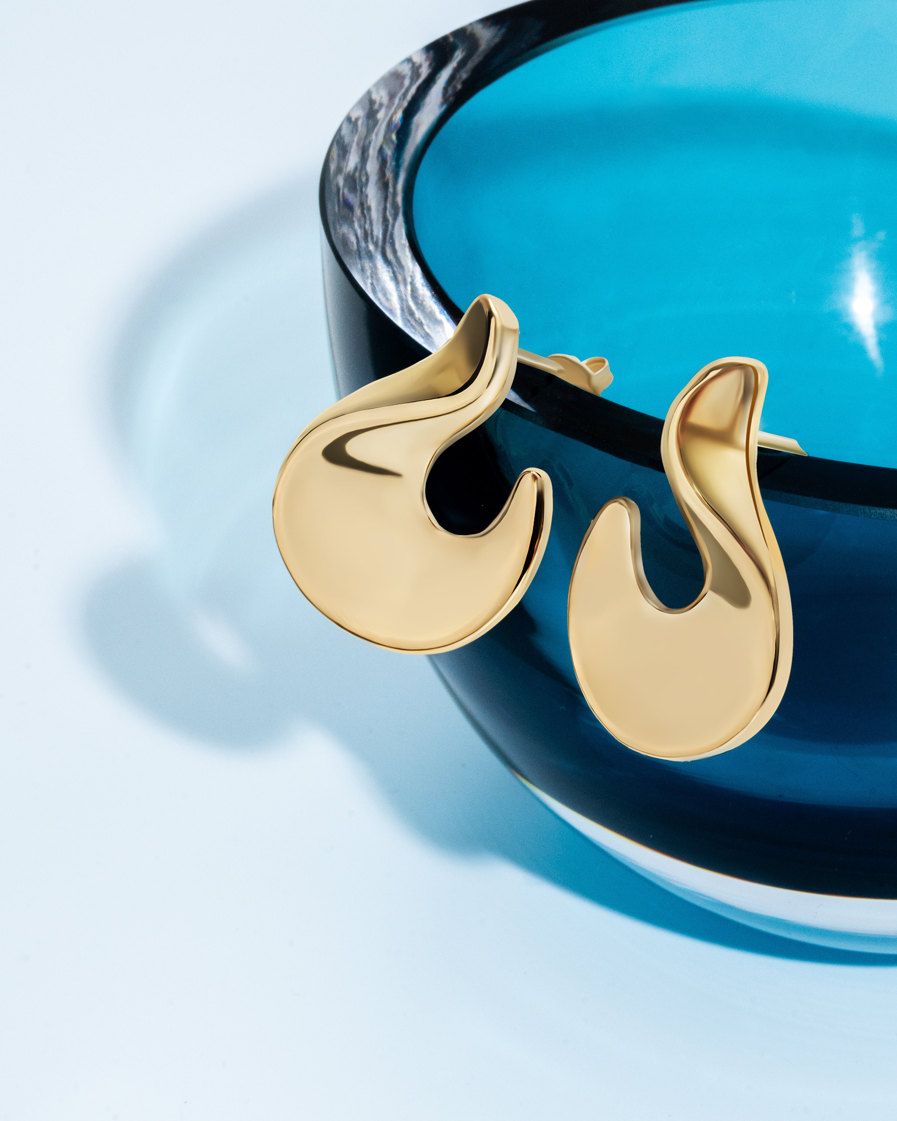 Abstract hook earrings available in gold plated and rhodium plated finishes with sculptural curved design