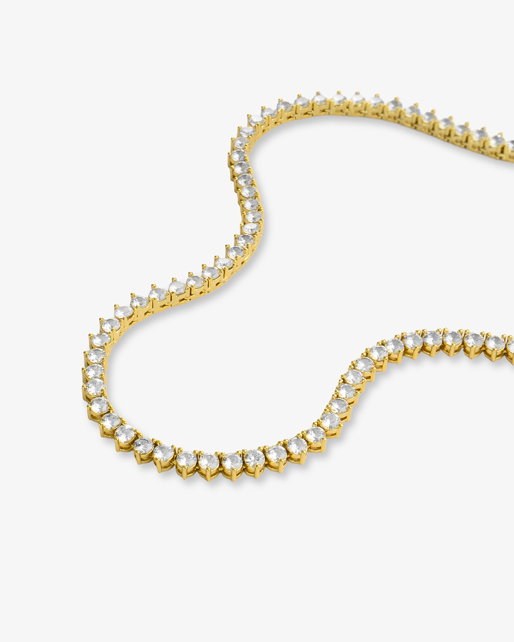 Gold three-prong tennis necklace with simulated diamond stones, alone product shot laid in a curved squiggle shape.