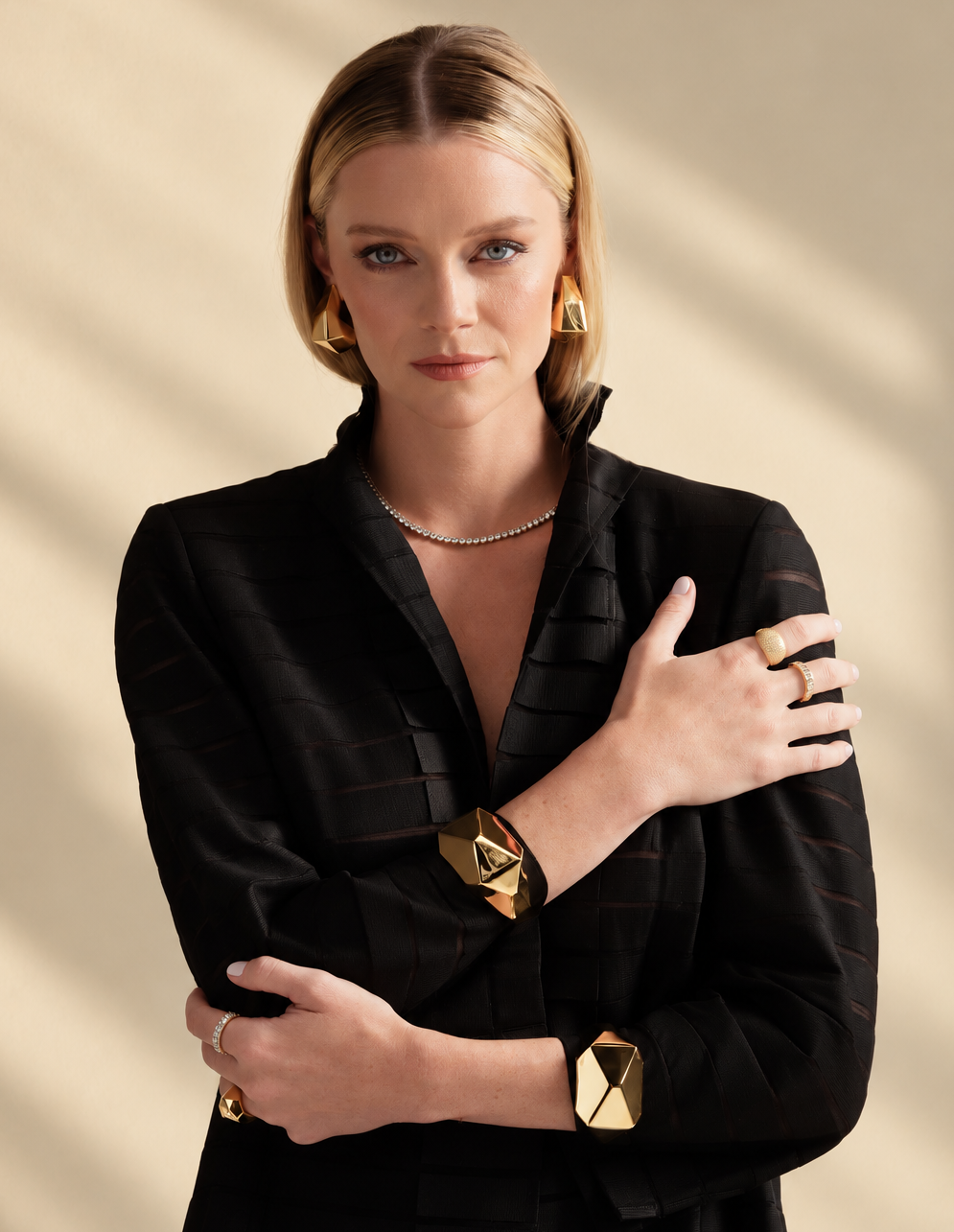 Lifestyle photo of a woman in a black top with her arms crossed, wearing the gold geometric cuff bracelet.