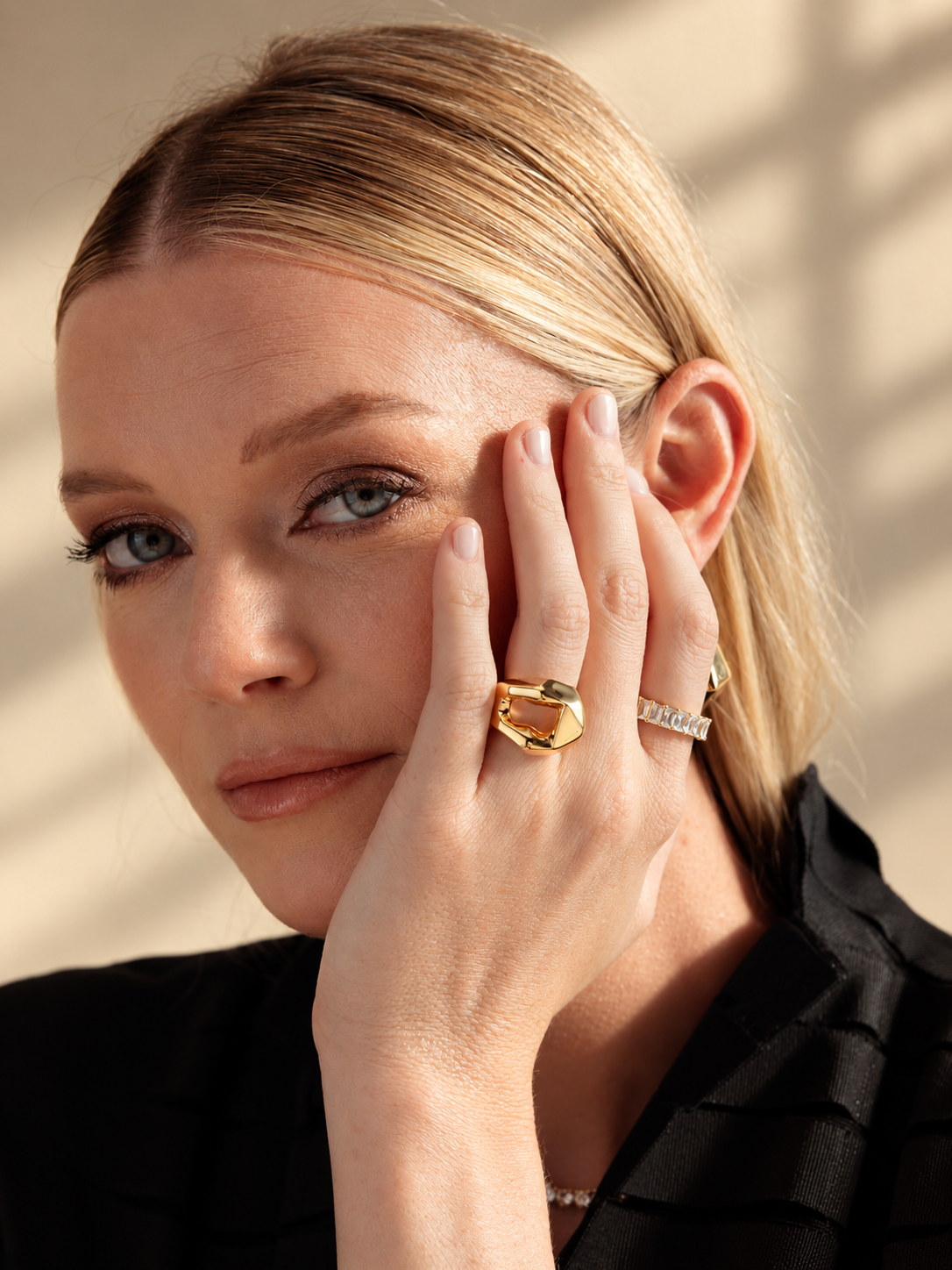 Lifestyle close-up of a woman in a black top with her hand near her ear, wearing the geometric faceted ring.