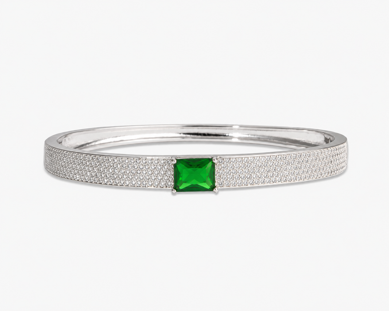 Gold pave bangle bracelet with a single blue simulated diamond stone, alone product shot on a plain background.