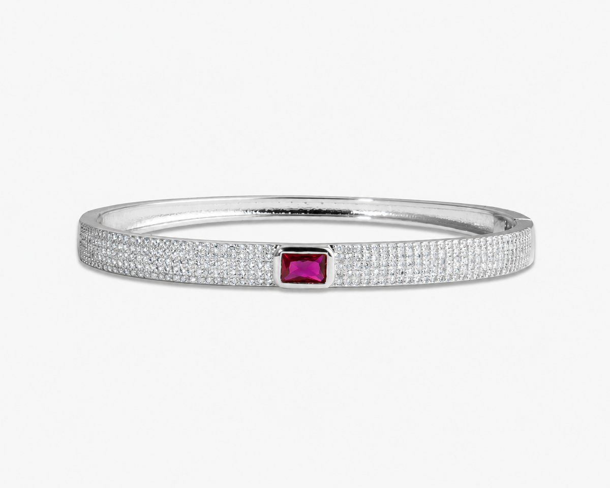 Silver textured bangle bracelet with a pink simulated diamond accent stone, alone product shot on a plain background.