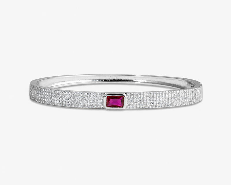 Silver textured bangle bracelet with a pink simulated diamond accent stone, alone product shot on a plain background.