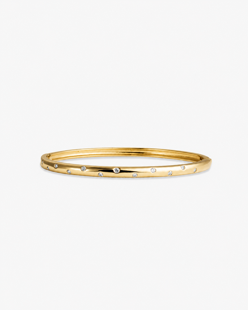 Gold slim textured bangle bracelet, alone product shot on a plain background.