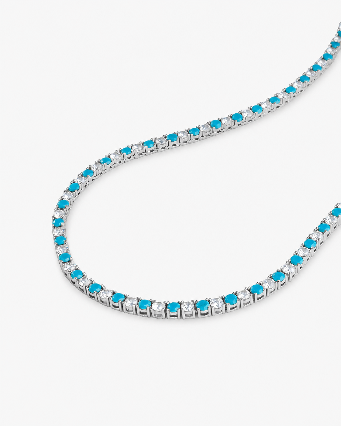 Silver tennis necklace with teal colored simulated diamond stones, alone product shot laid in a curved squiggle shape.