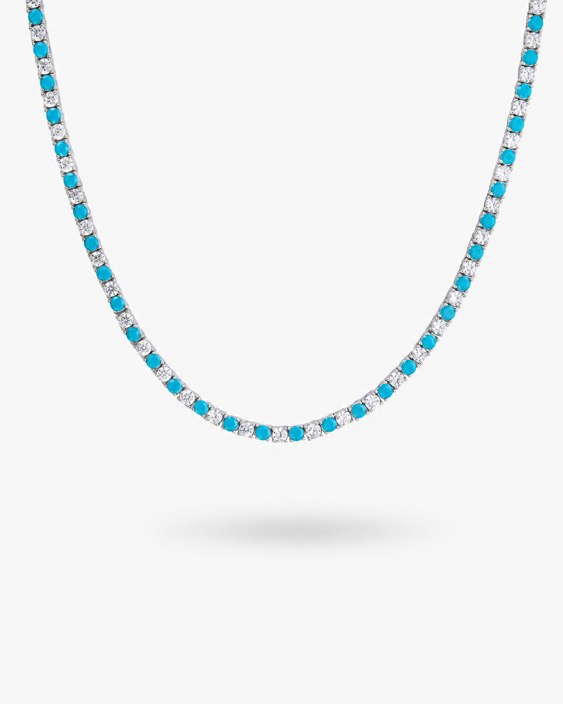 Tennis necklace with blue sapphire-colored simulated diamond stones, alone product shot on a plain background.