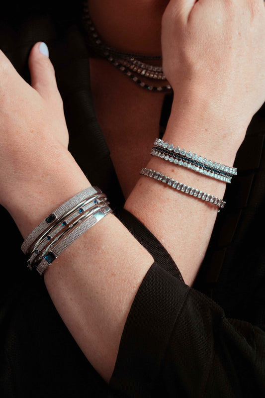 Close-up of a wrist stacked with the Laura silver tennis bracelet and a black beaded bracelet