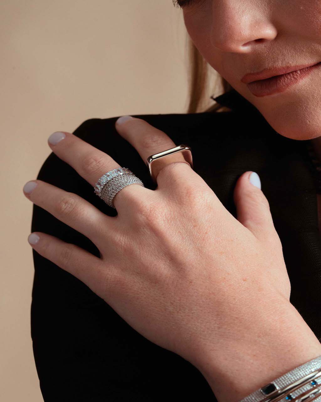 Close-up of a hand near the chest, wearing the Lily silver signet ring and a bracelet, black top