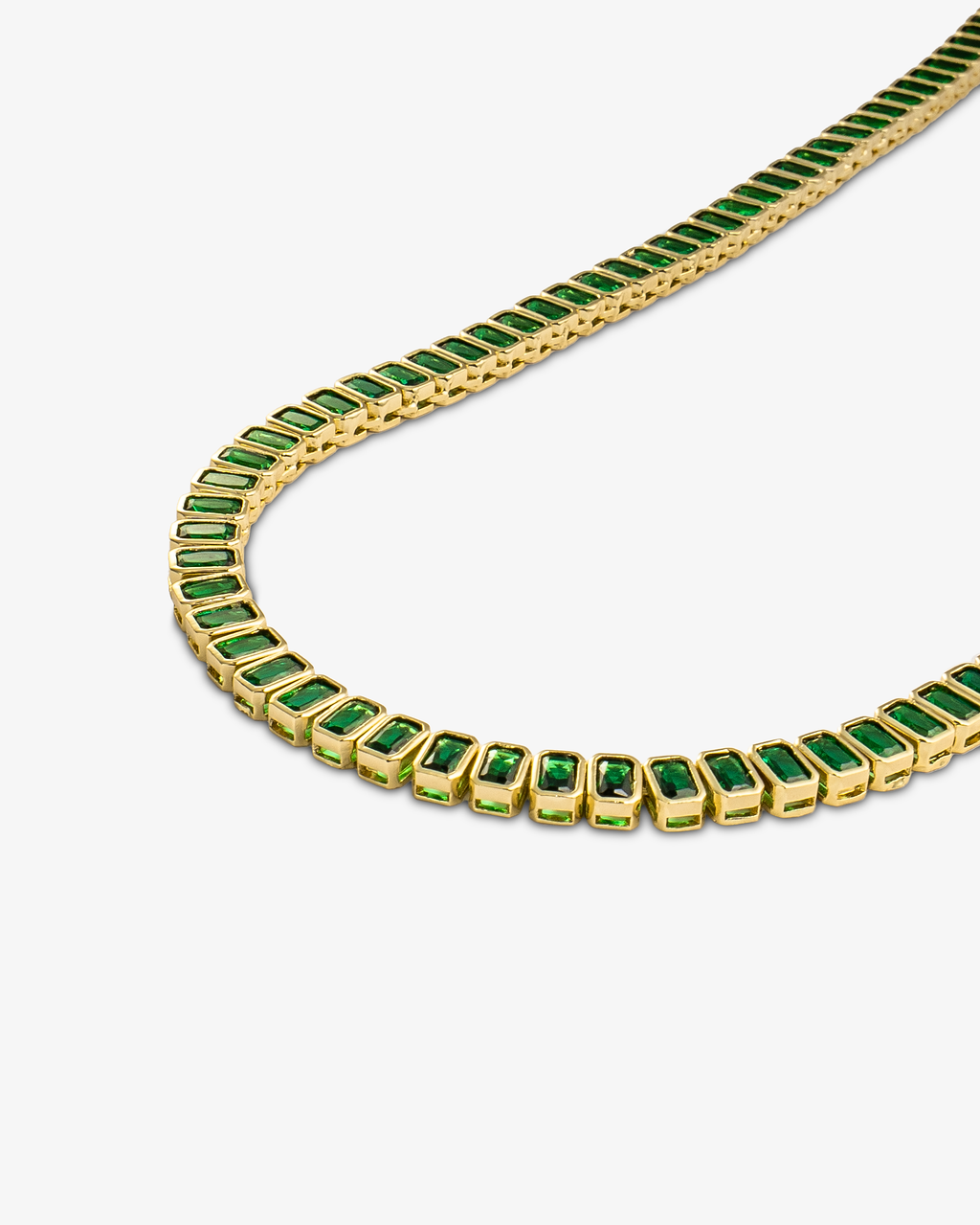 Gold tennis necklace with green baguette-cut simulated diamond stones, alone product shot from a curved angle.