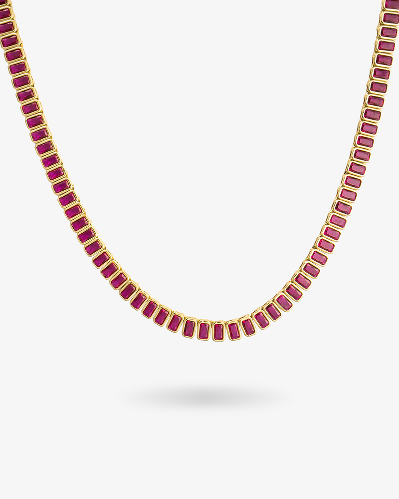 Gold tennis necklace with red baguette-cut simulated diamond stones, alone product shot on a plain background.