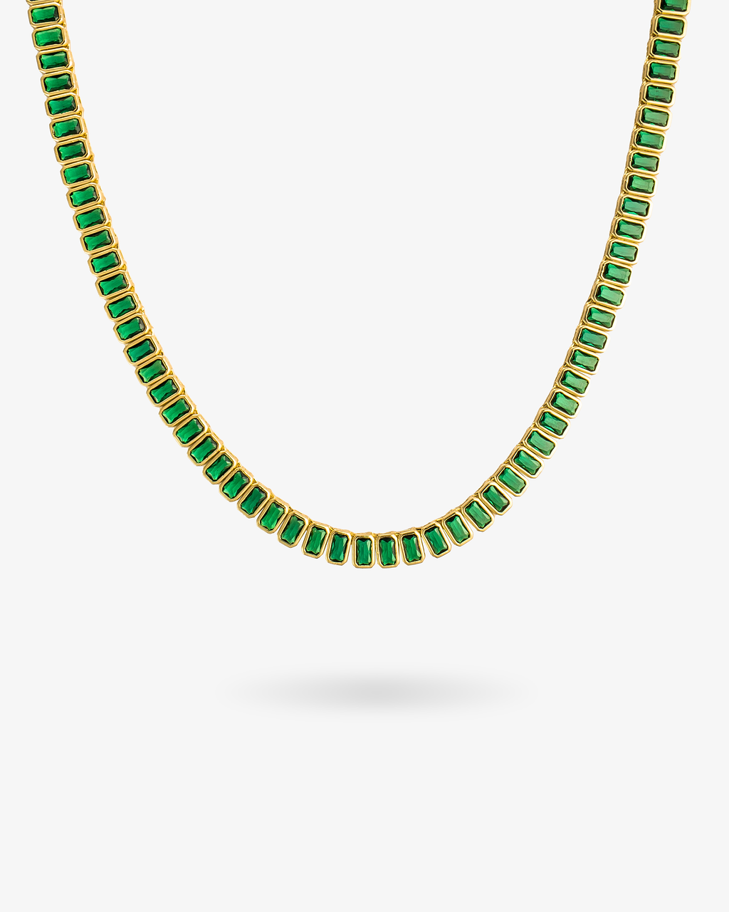 Gold tennis necklace with green baguette-cut simulated diamond stones, alone product shot on a plain background.