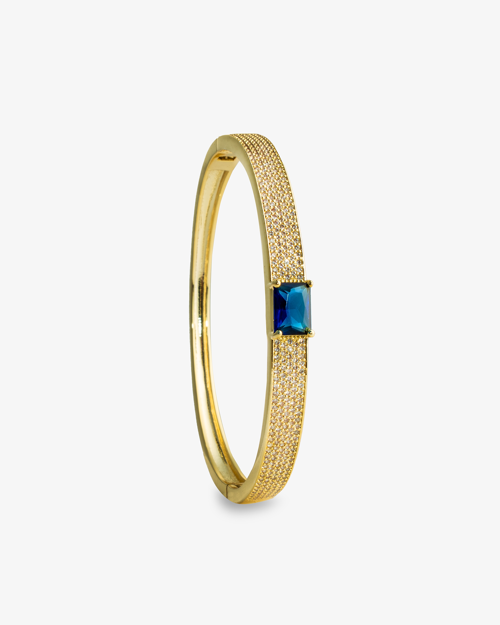 Gold open cuff bangle bracelet with a single blue simulated diamond stone, alone product shot shown vertically.