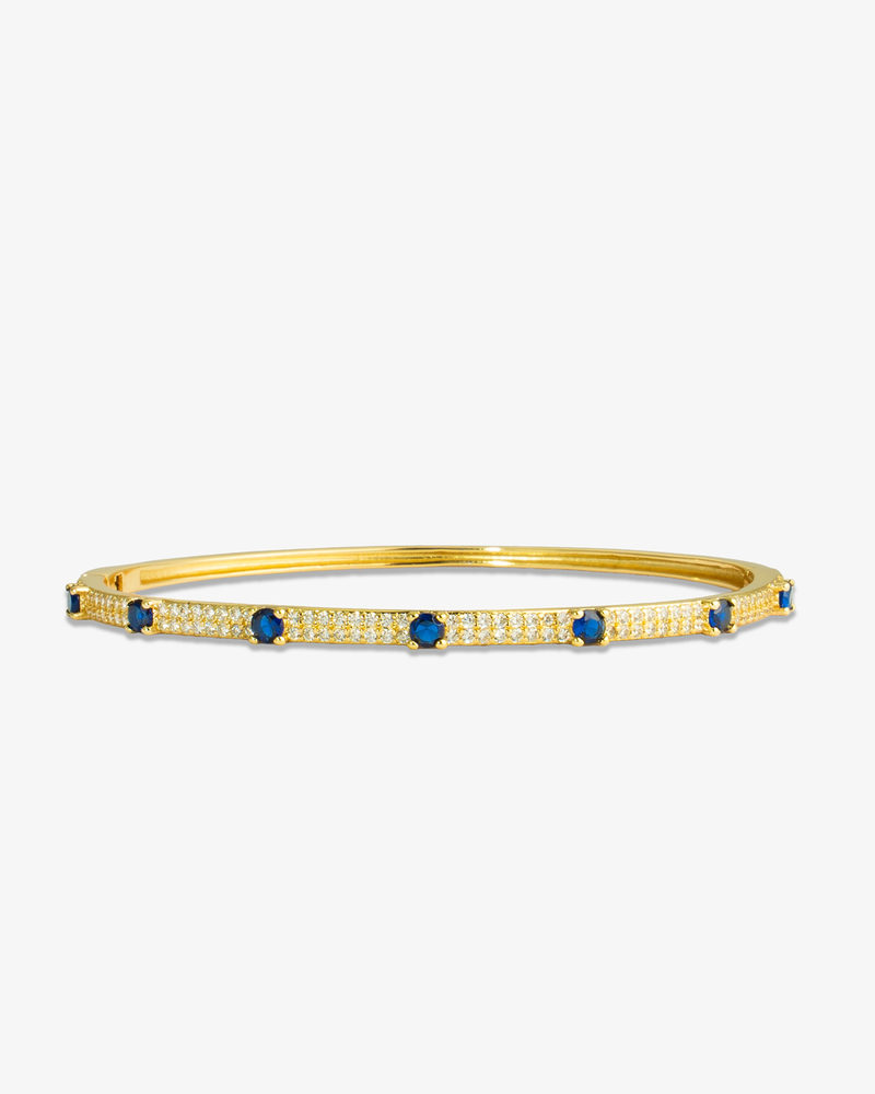 Gold thin bangle bracelet with blue simulated diamond stone detailing, alone product shot on a plain background.
