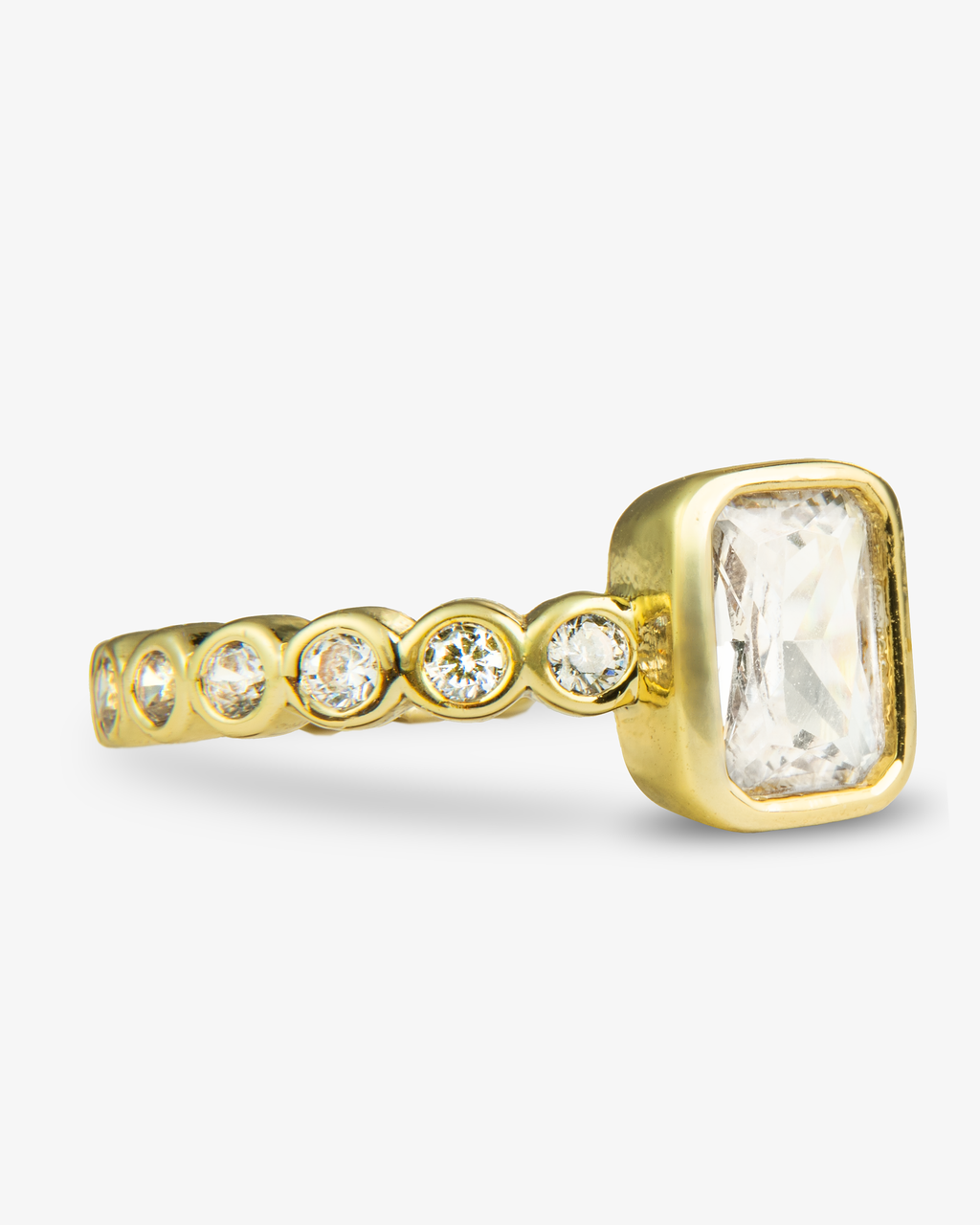 Gold ring with a clear emerald-cut simulated diamond center stone and pave band, alone close-up product shot.