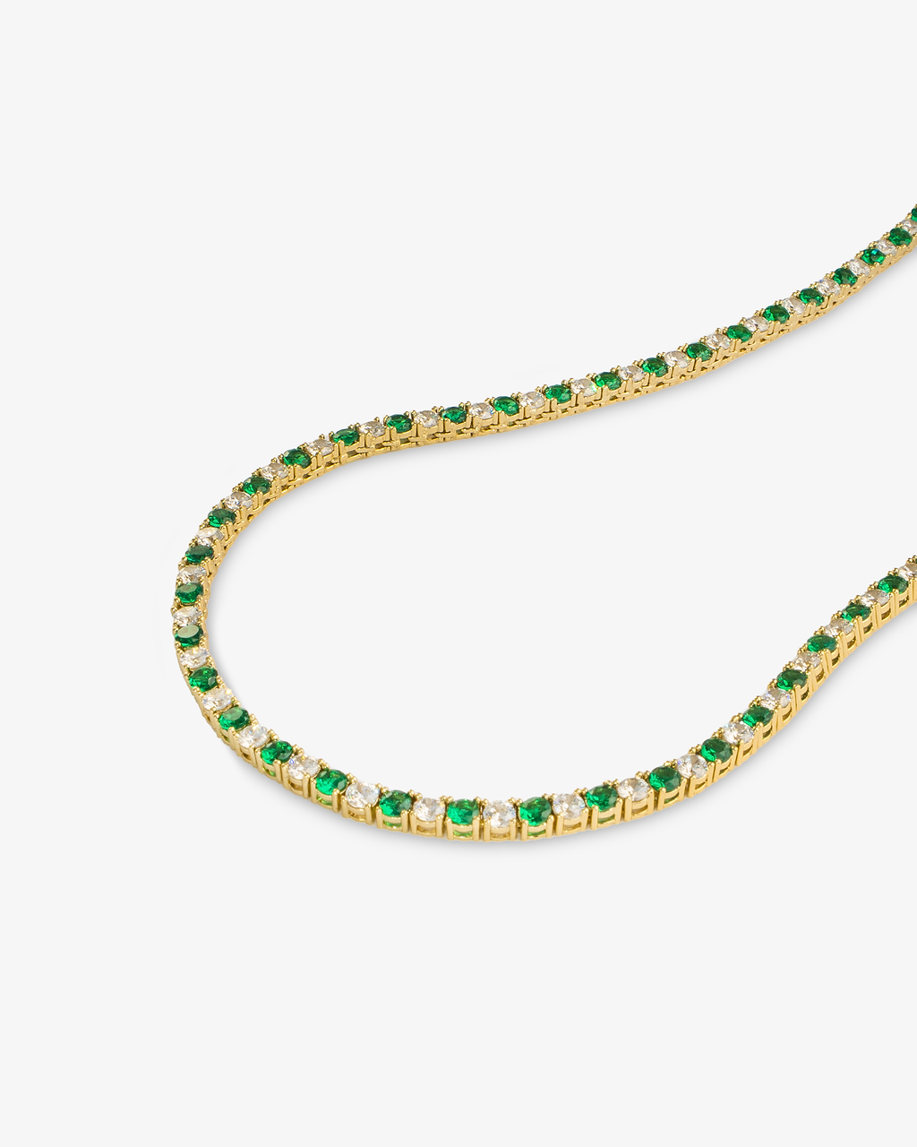 Tennis necklace with green emerald-colored simulated diamond stones, alone close-up product shot laid in a curved squiggle shape.