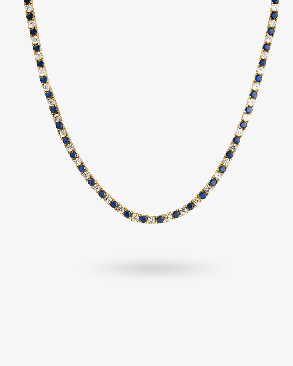 Tennis necklace with blue sapphire-colored simulated diamond stones, alone product shot laid in a curved squiggle shape.