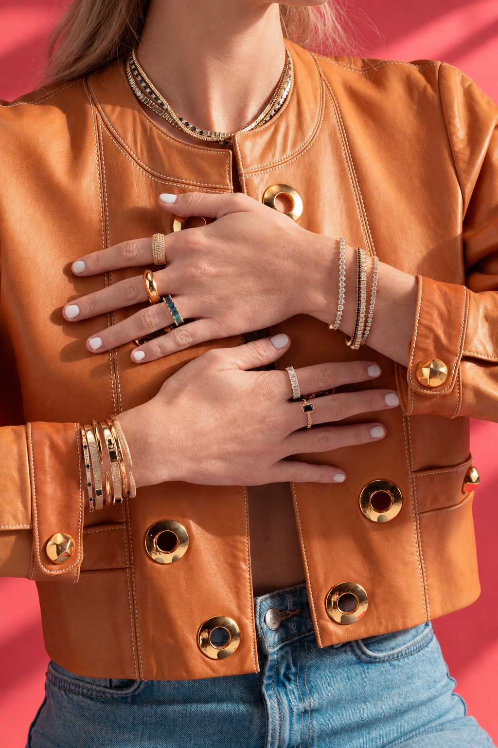 Lifestyle photo of hands crossed over a caramel leather jacket, wearing the silver square tennis bracelet stacked with other bracelets and rings.