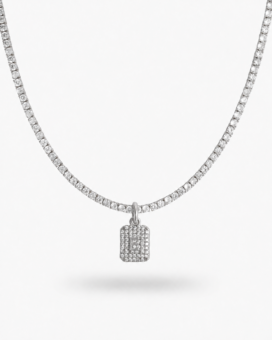 Silver tennis necklace with a pave simulated diamond initial letter pendant, alone product shot on a plain background.