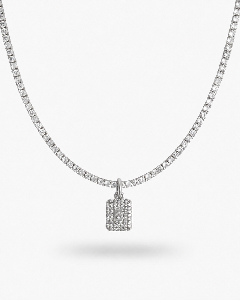 Silver tennis necklace with a pave simulated diamond initial letter pendant, alone product shot on a plain background.