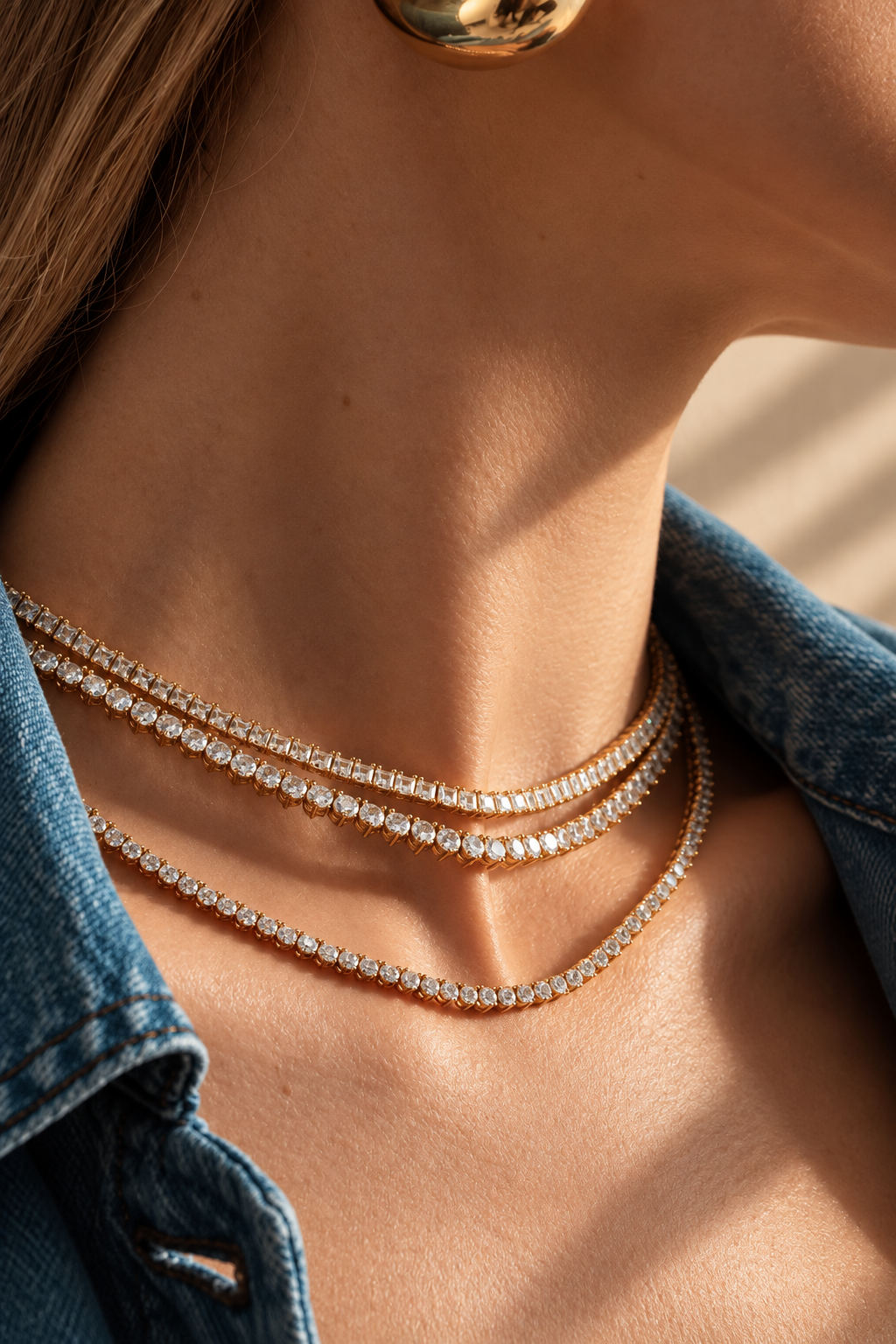 Lifestyle close-up of a woman's neckline in a denim jacket, styled with a tennis necklace layered together with a small pendant necklace.