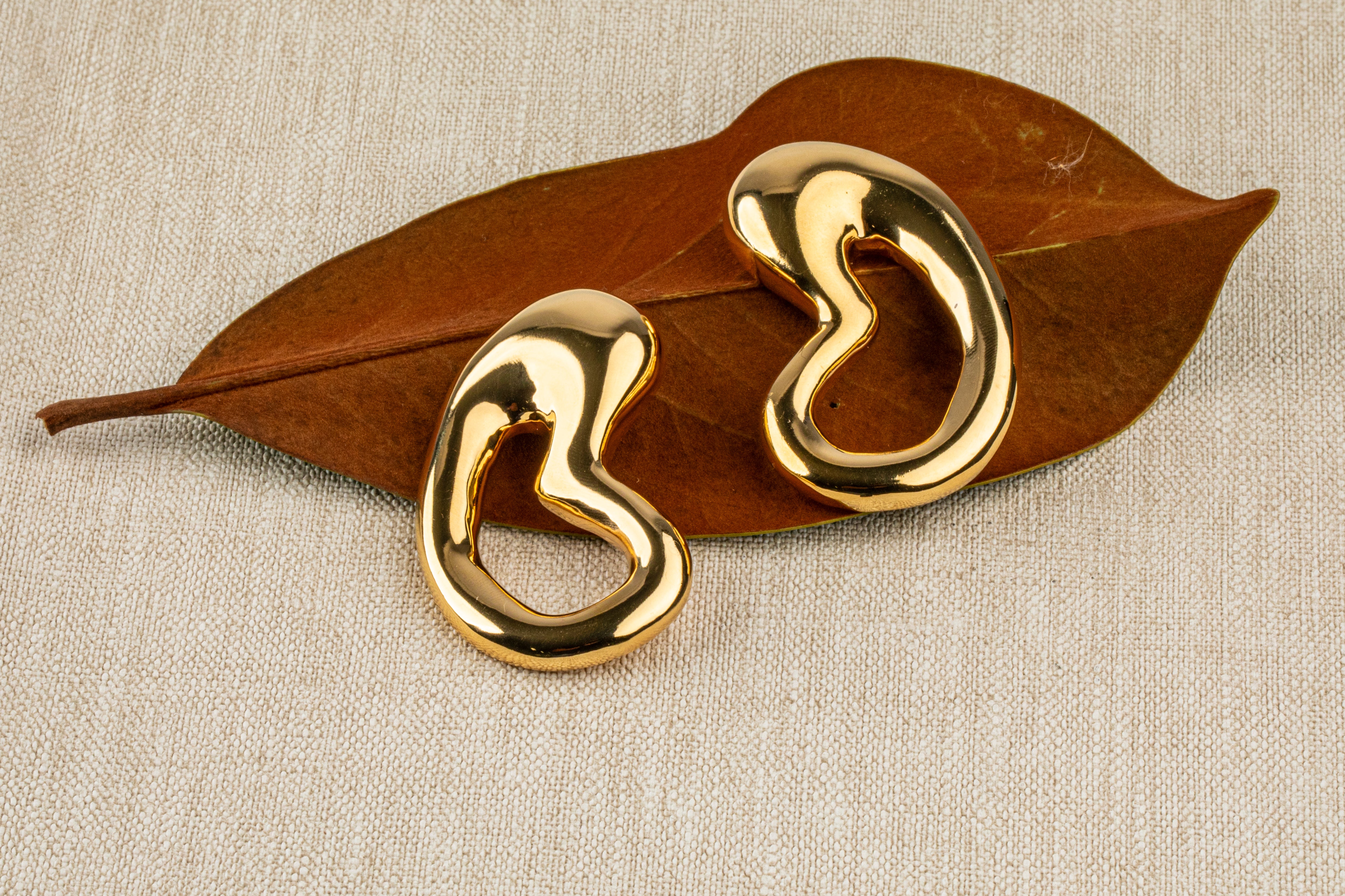 Gold plated organic sculptural earrings with fluid asymmetric curved design and polished finish, 61mm by 30mm
