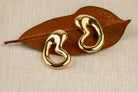 Gold plated organic sculptural earrings with fluid asymmetric curved design and polished finish, 61mm by 30mm