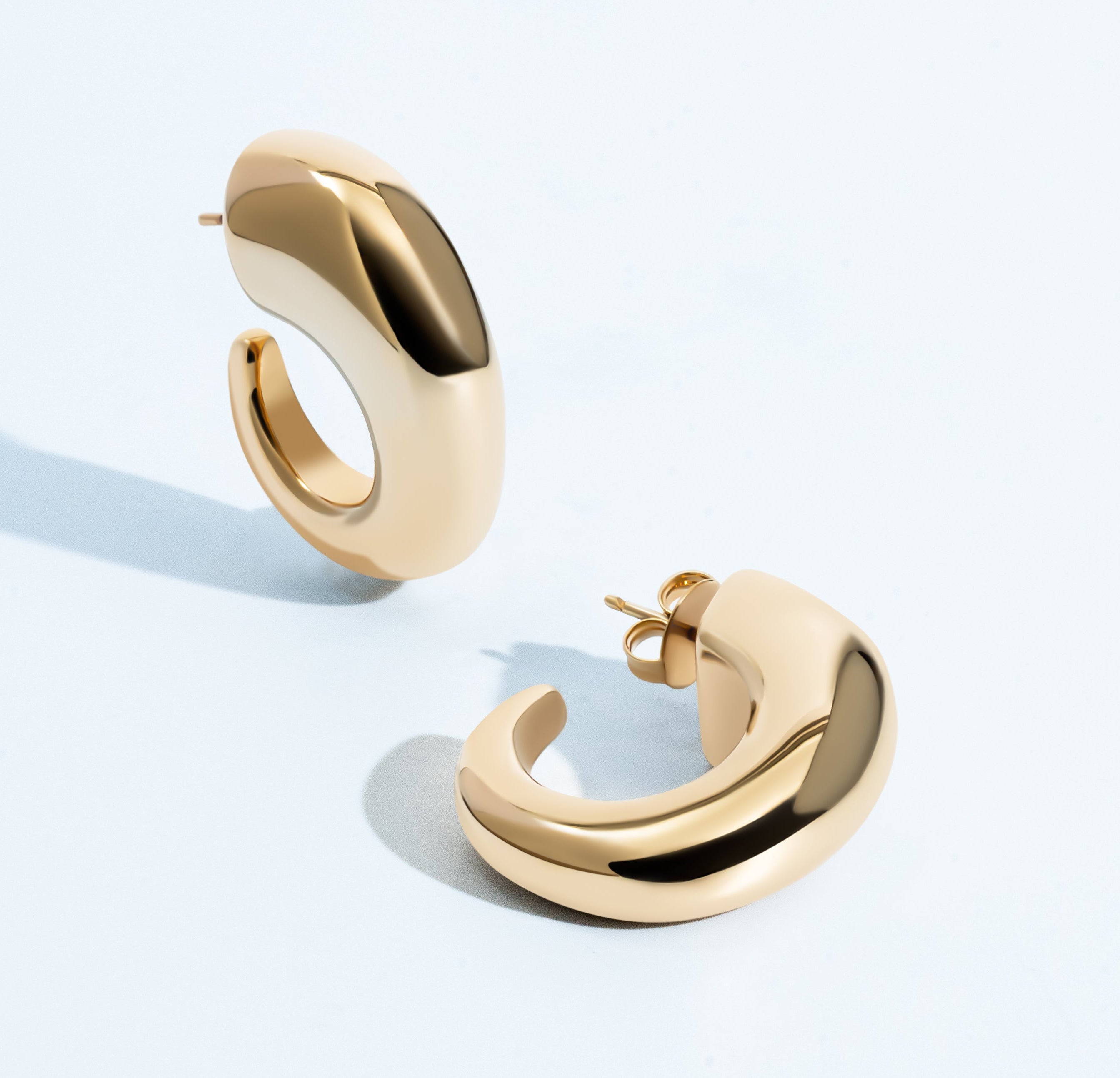 Oval open hoop earrings available in gold plated and rhodium plated finishes with sculptural thick design