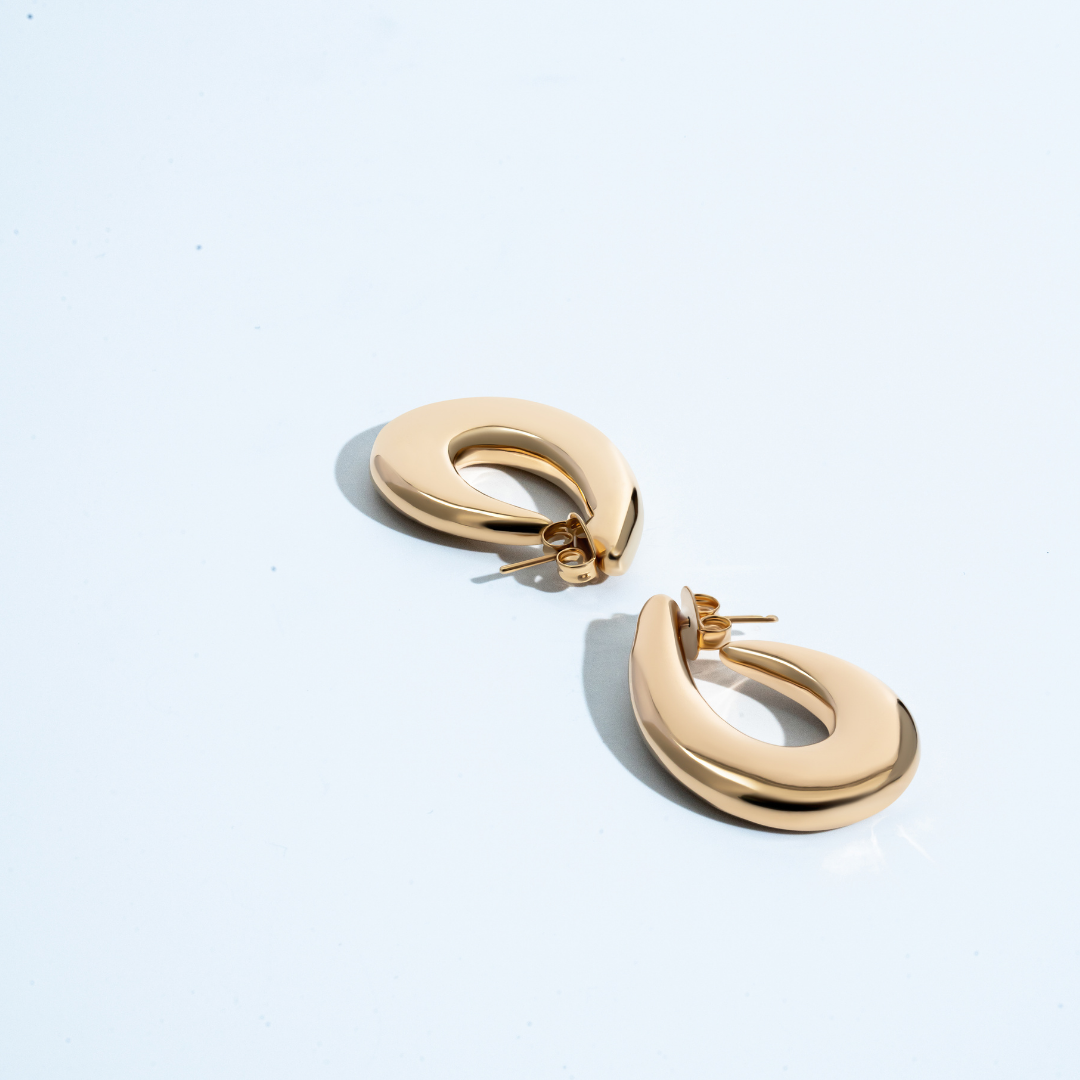 Sculptural hoop earrings available in gold plated and rhodium plated finishes with curved modern design