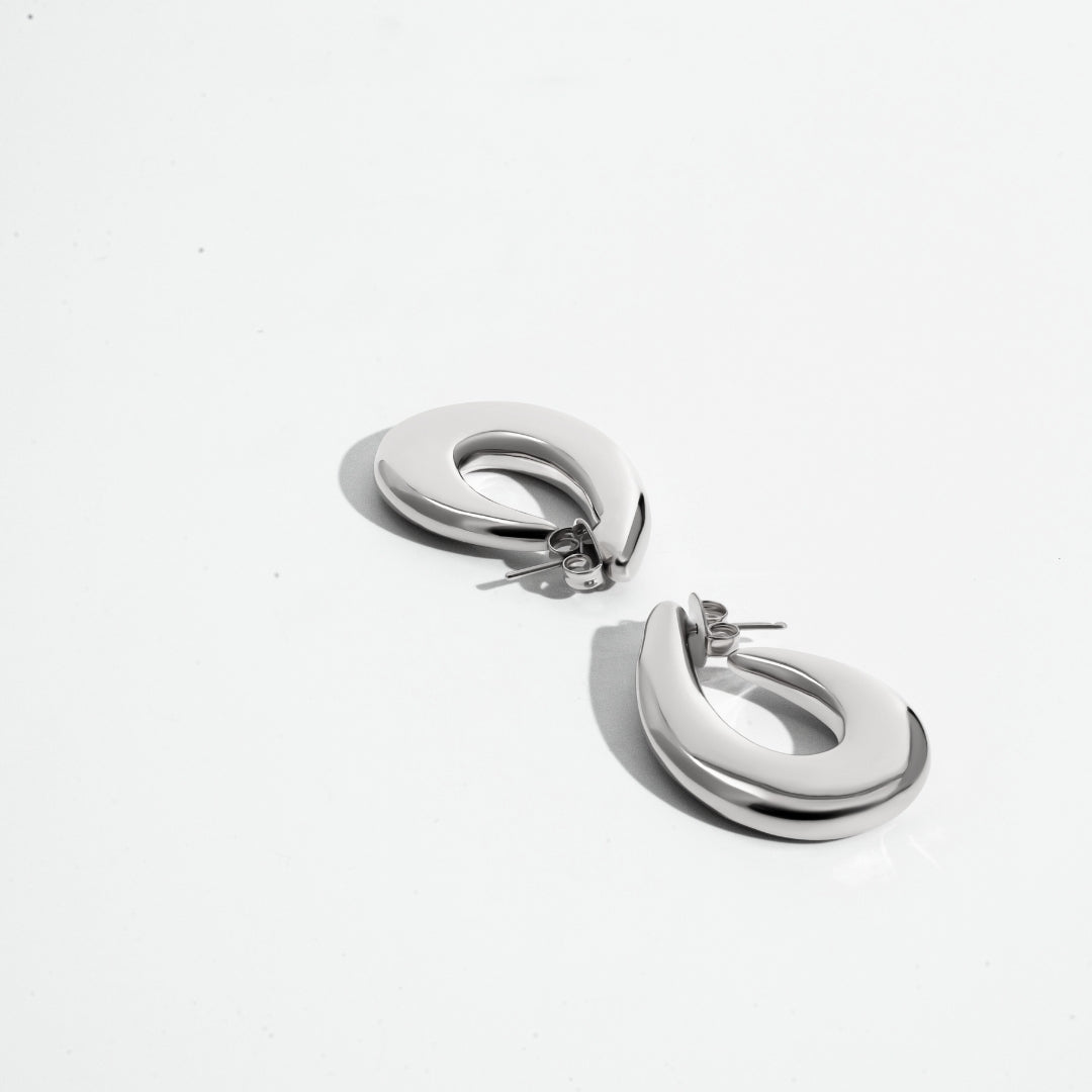 Sculptural hoop earrings available in gold plated and rhodium plated finishes with curved modern design