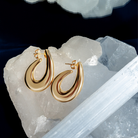 Sculptural hoop earrings available in gold plated and rhodium plated finishes with curved modern design