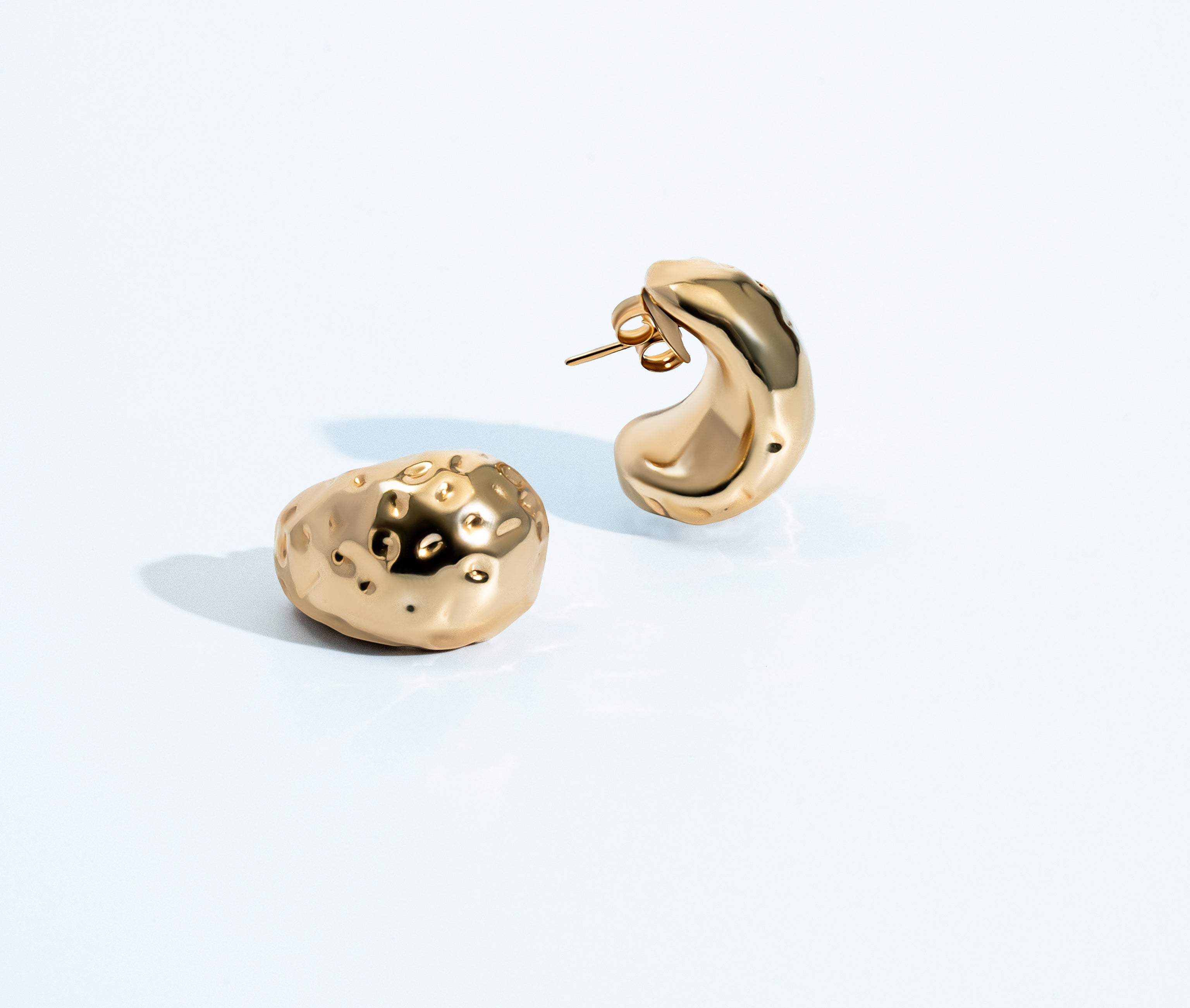 Gold sculptural earrings with compact organic texture and polished finish