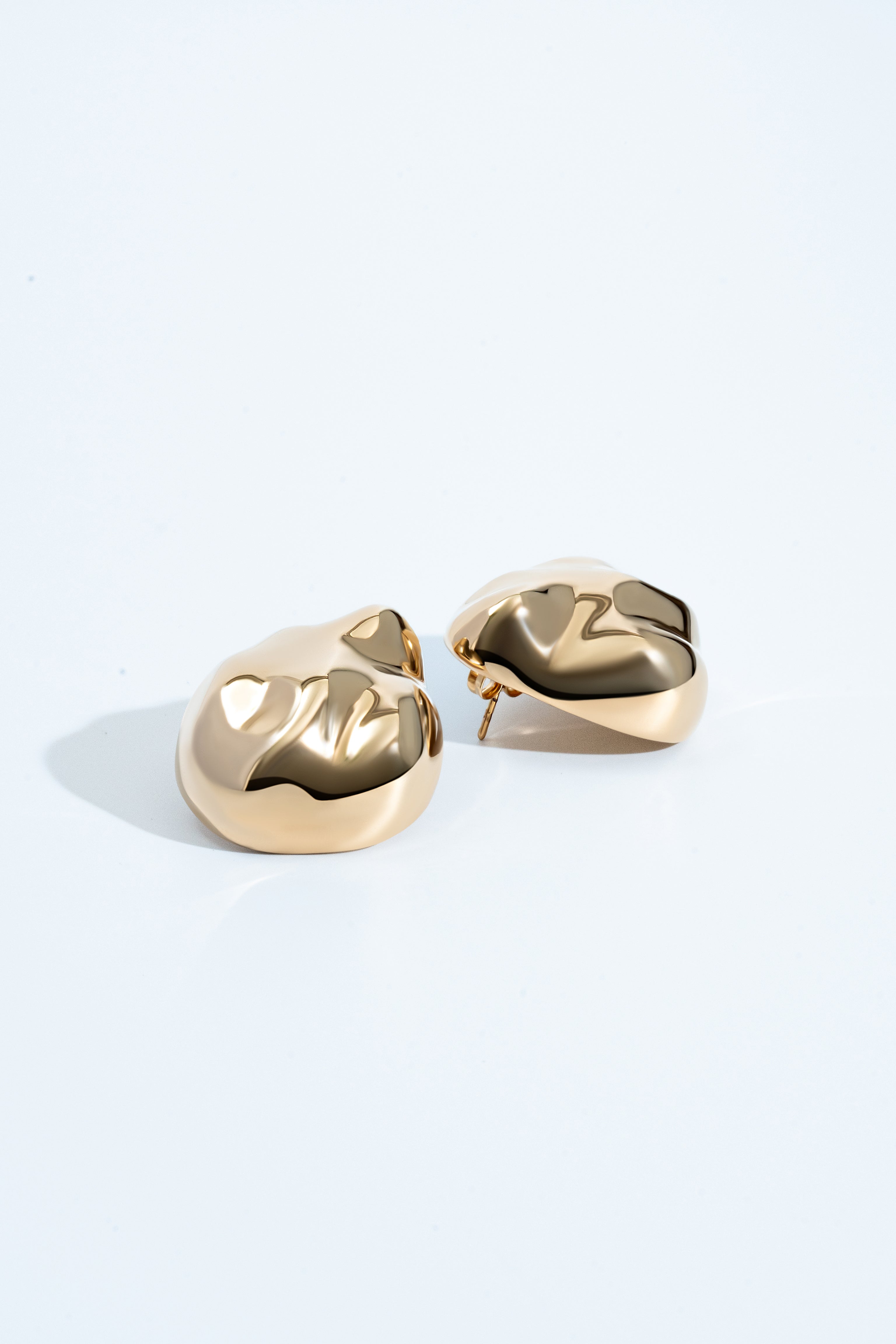 Dome earrings available in gold plated and rhodium plated finishes with dented sculptural texture