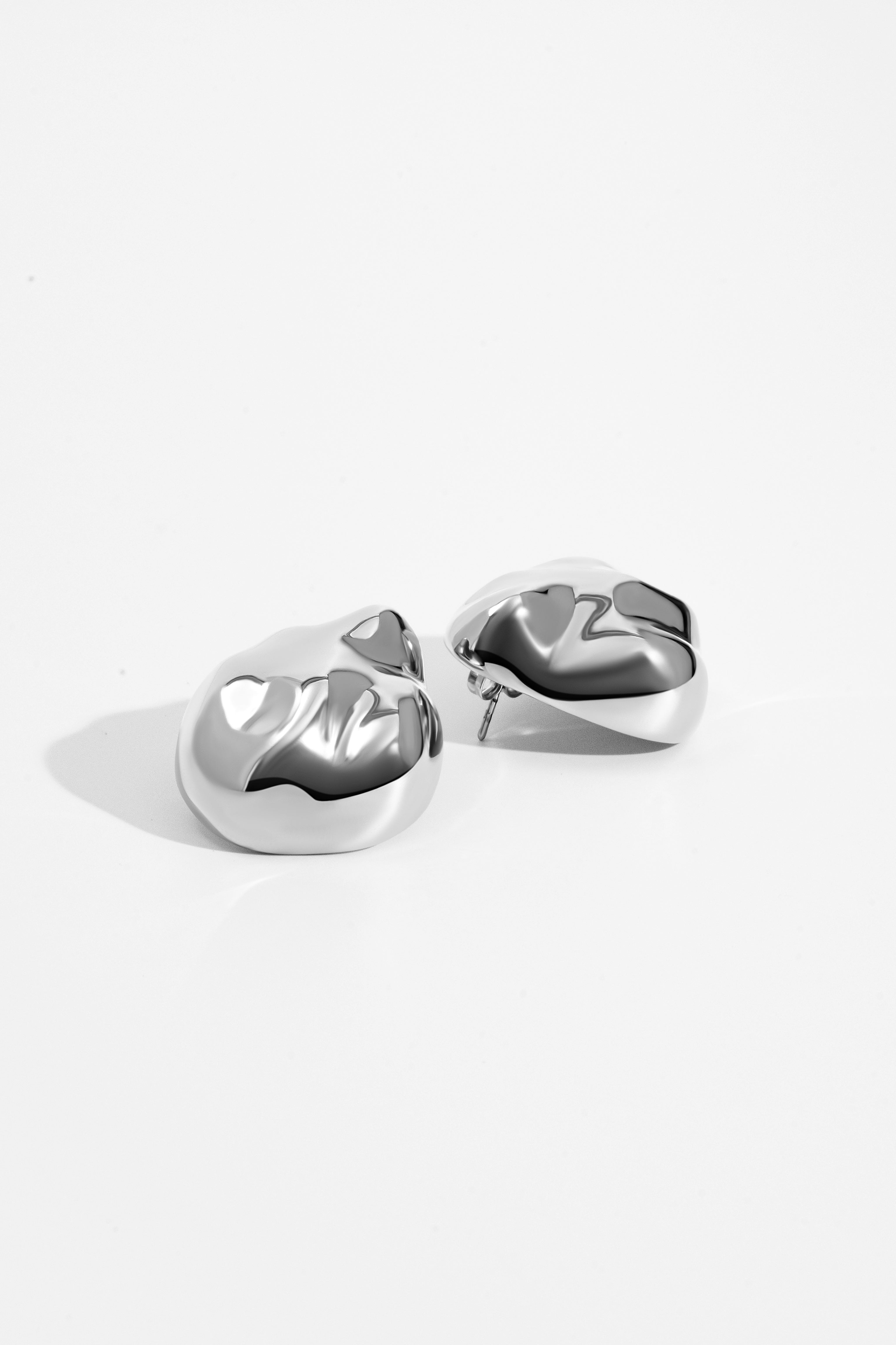 Dome earrings available in gold plated and rhodium plated finishes with dented sculptural texture