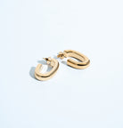 Oval open hoop earrings available in gold plated and rhodium plated finishes with sculptural curved design