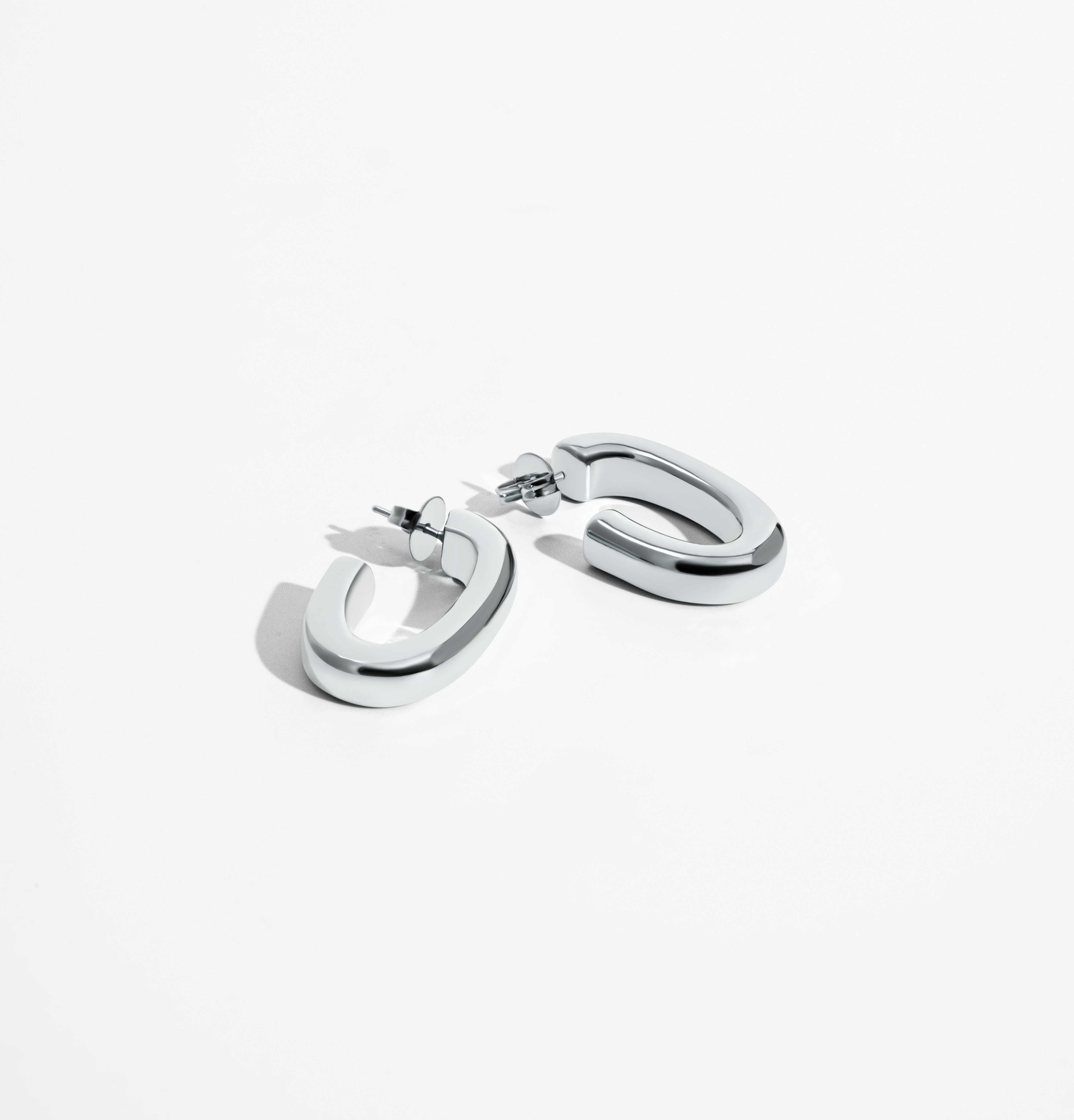 Oval open hoop earrings available in gold plated and rhodium plated finishes with sculptural curved design
