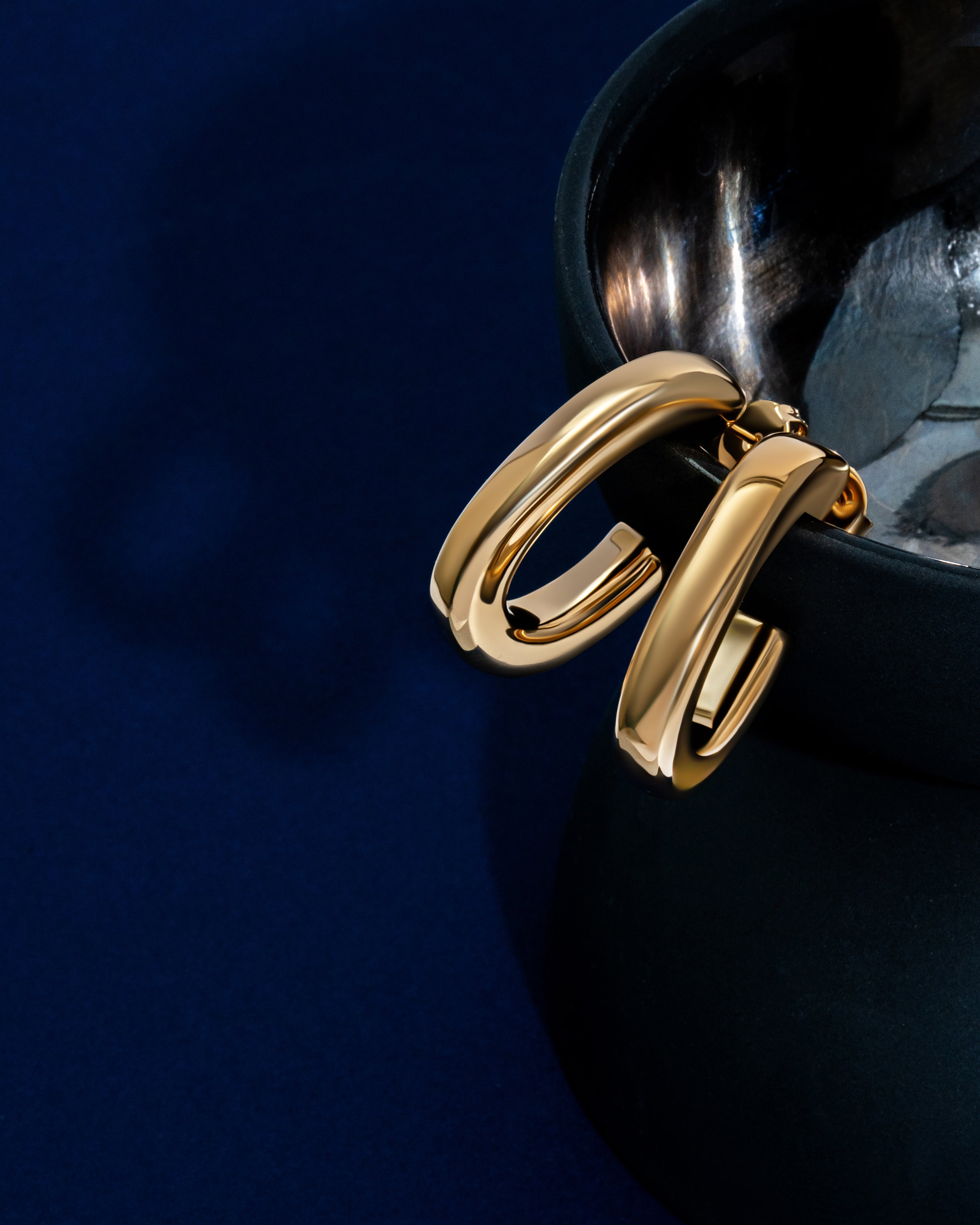 Oval open hoop earrings available in gold plated and rhodium plated finishes with sculptural curved design