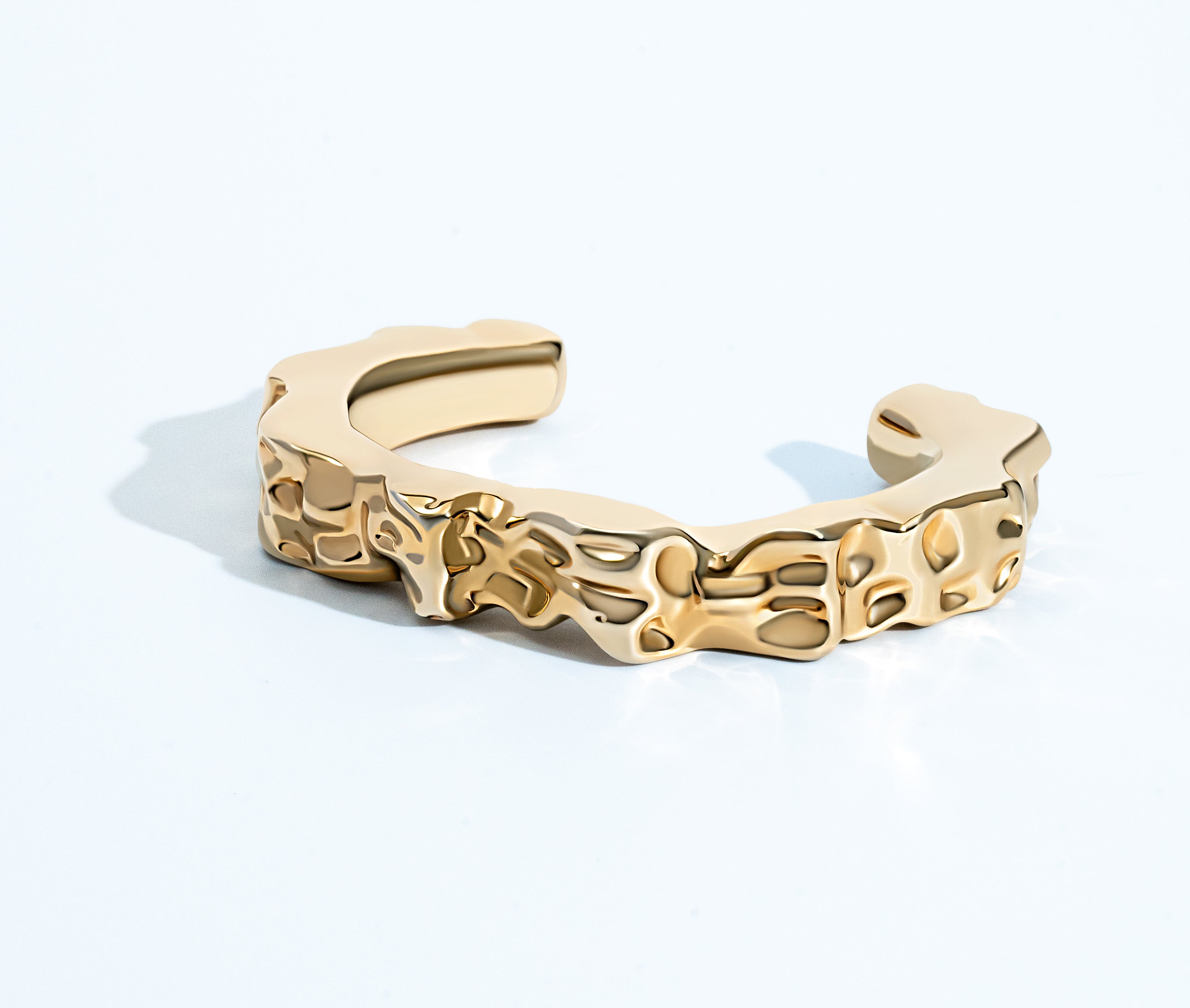 Sculpted hammered cuff bracelet available in gold plated and rhodium plated finishes with organic texture