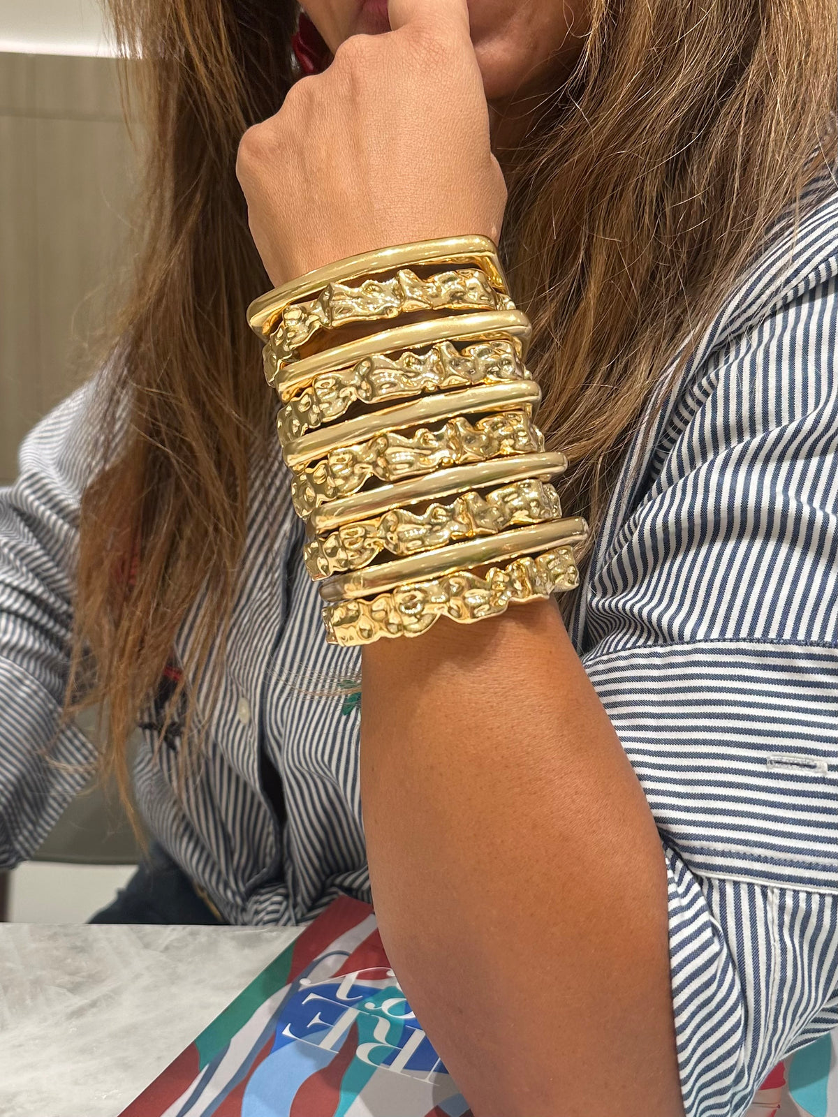 Sculptural gold cuff bracelet with irregular hammered texture on the arm