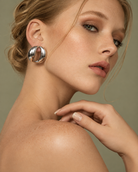a model wearing a Sculptural oval open-center silver statement earrings with smooth polished finish
