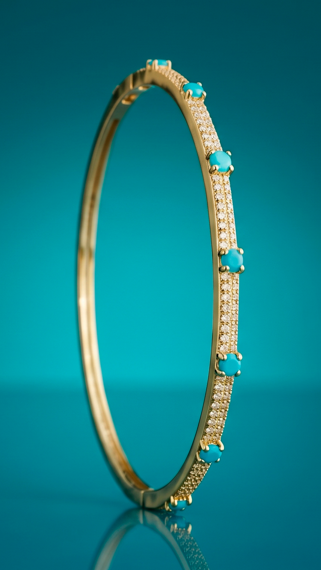 Gold-tone bangle bracelet featuring turquoise-blue stones and rows of small clear stones, displayed against a teal background.