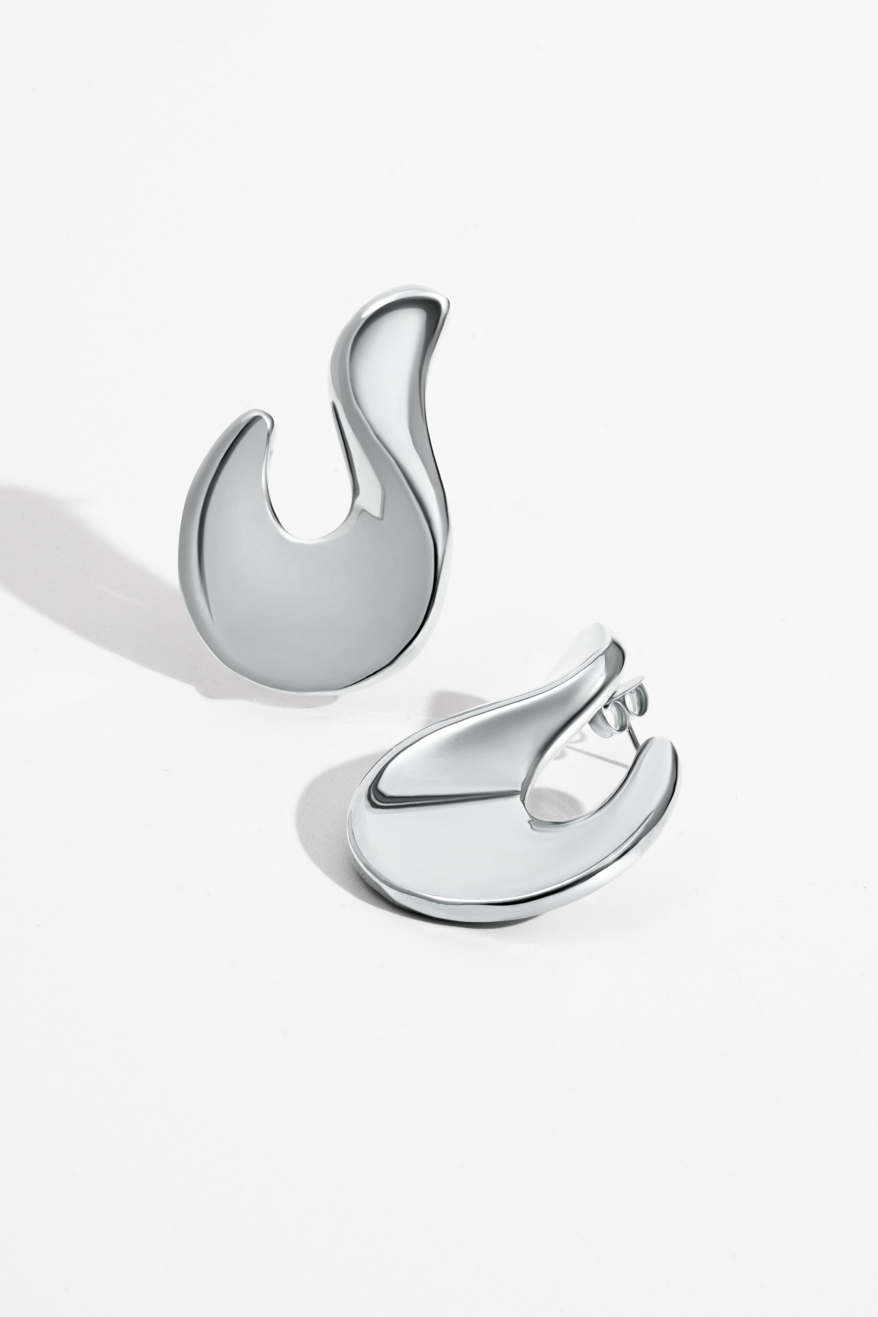 Abstract hook earrings available in gold plated and rhodium plated finishes with sculptural curved design