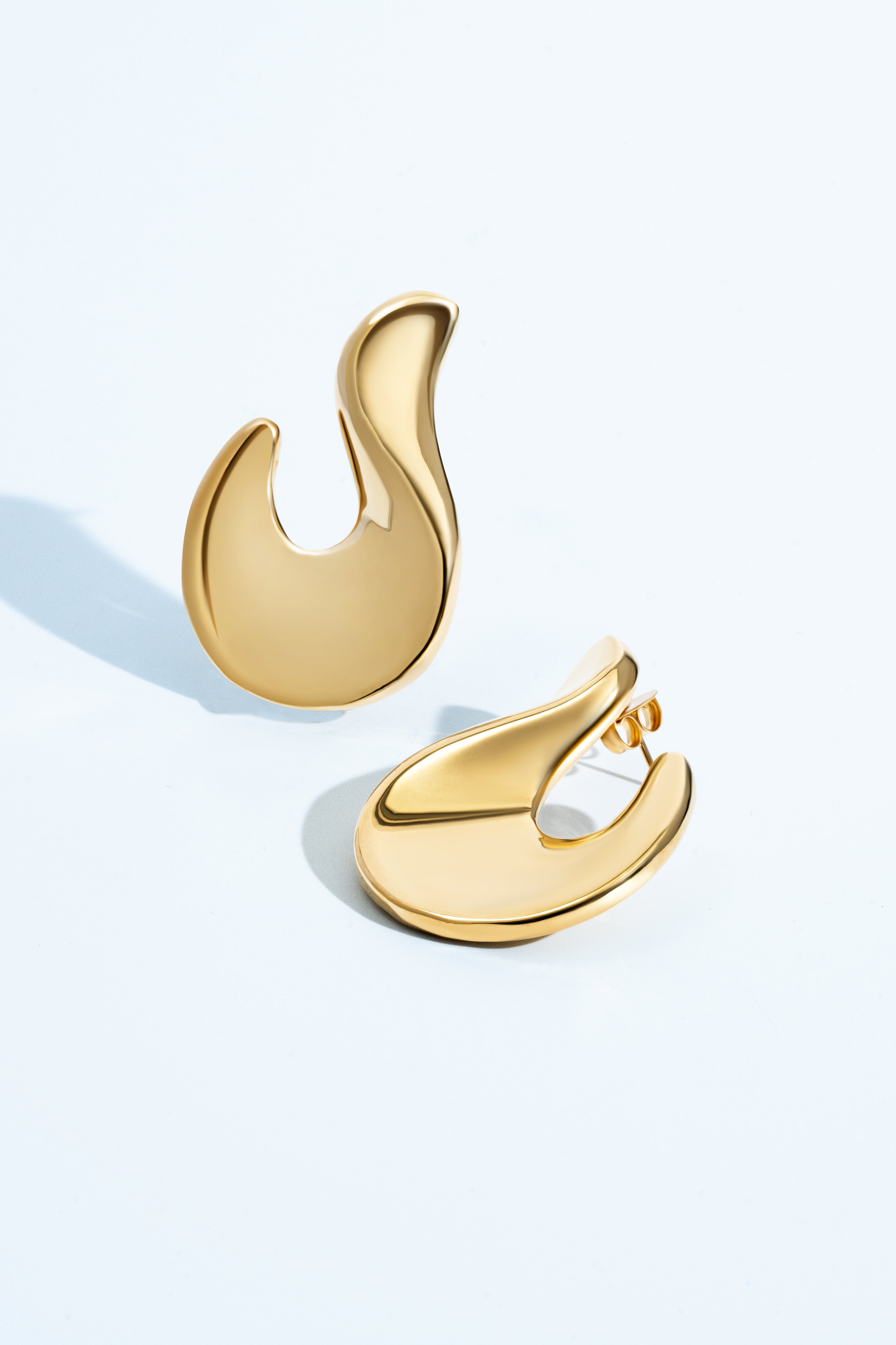 Abstract hook earrings available in gold plated and rhodium plated finishes with sculptural curved design